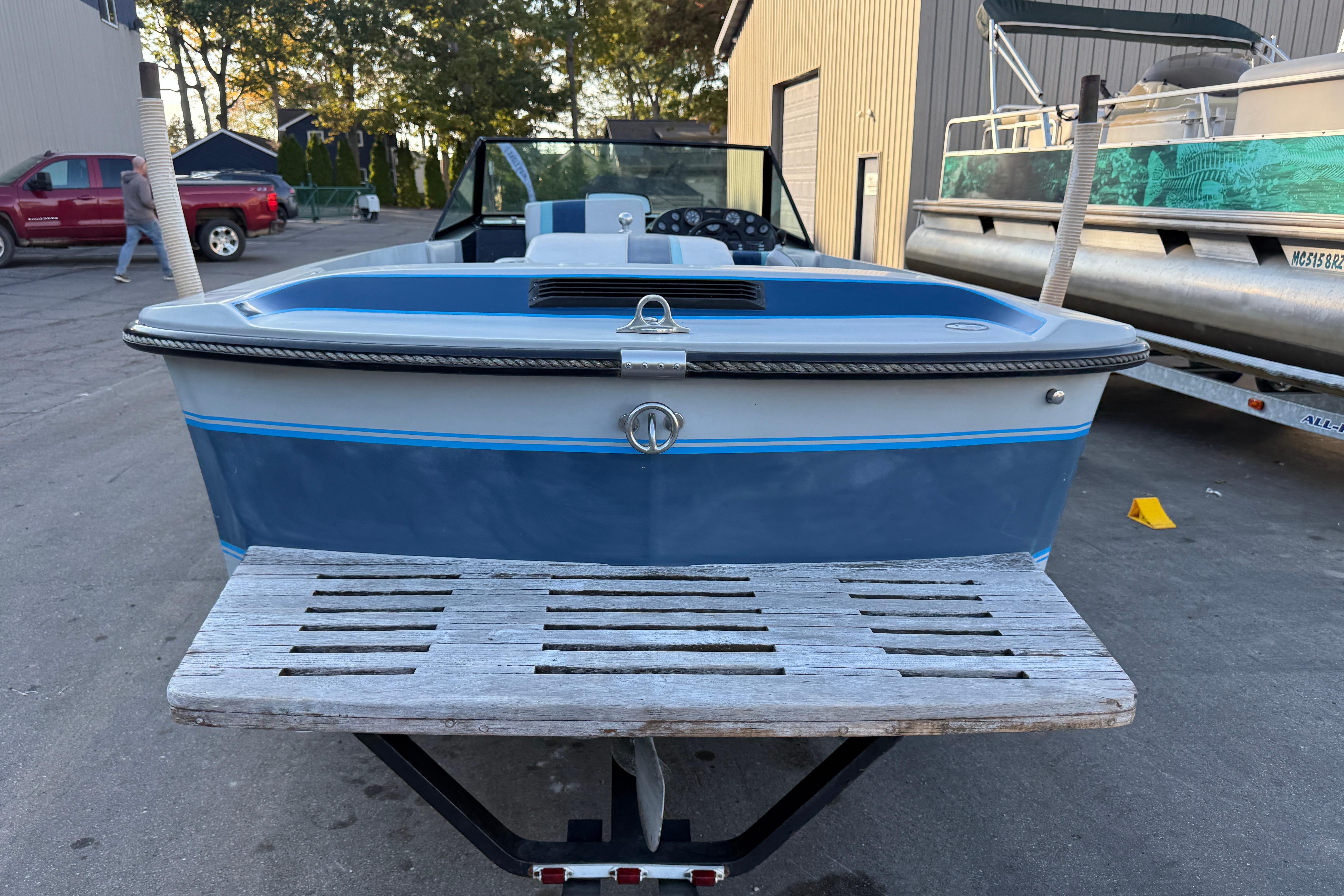 1989 Correct Craft Ski Nautique boat on trailer, parked outdoors near buildings.