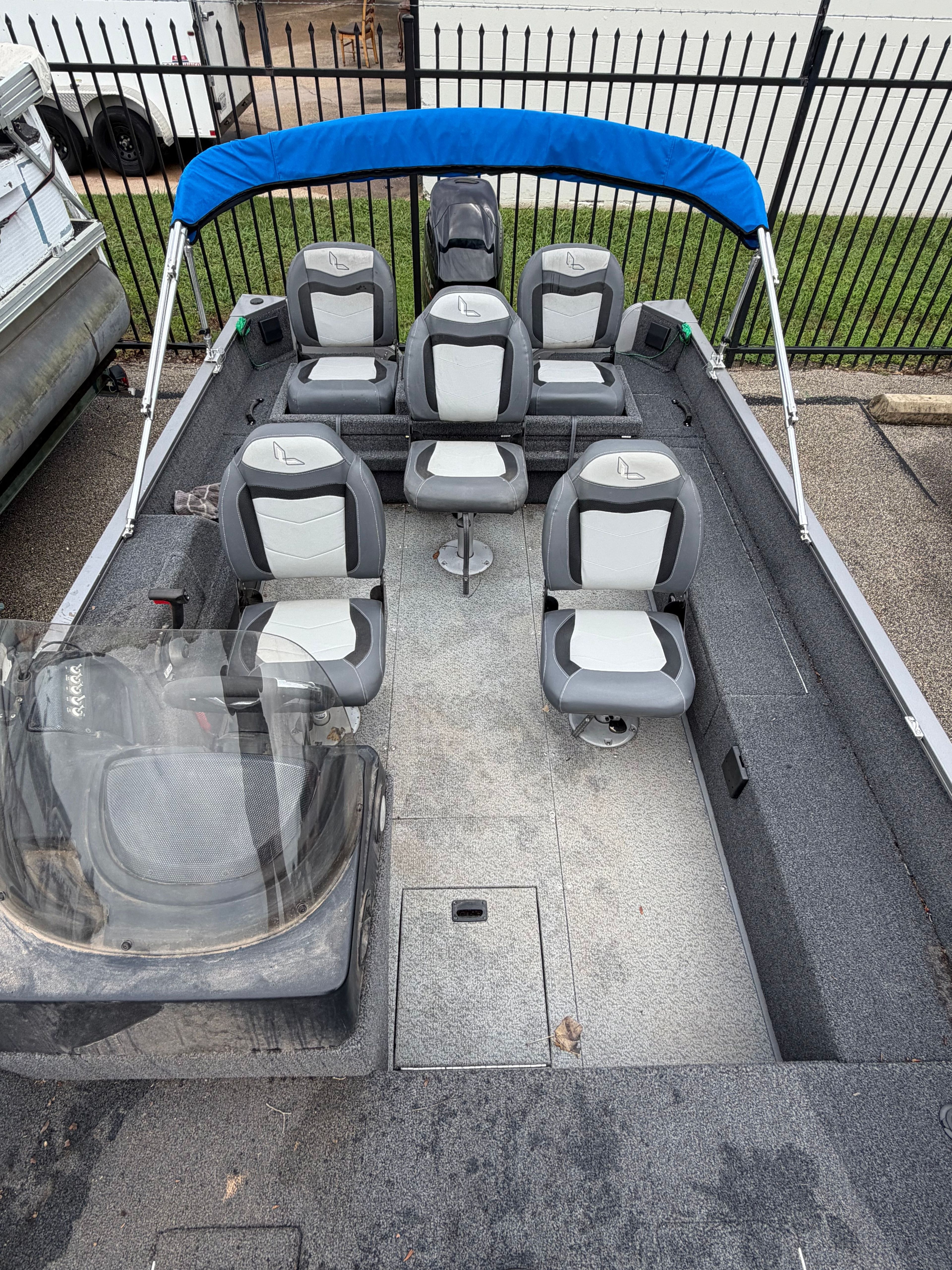 The image shows a Lowe Fishing Machine 1675SC boat with multiple seats and a blue sunshade.