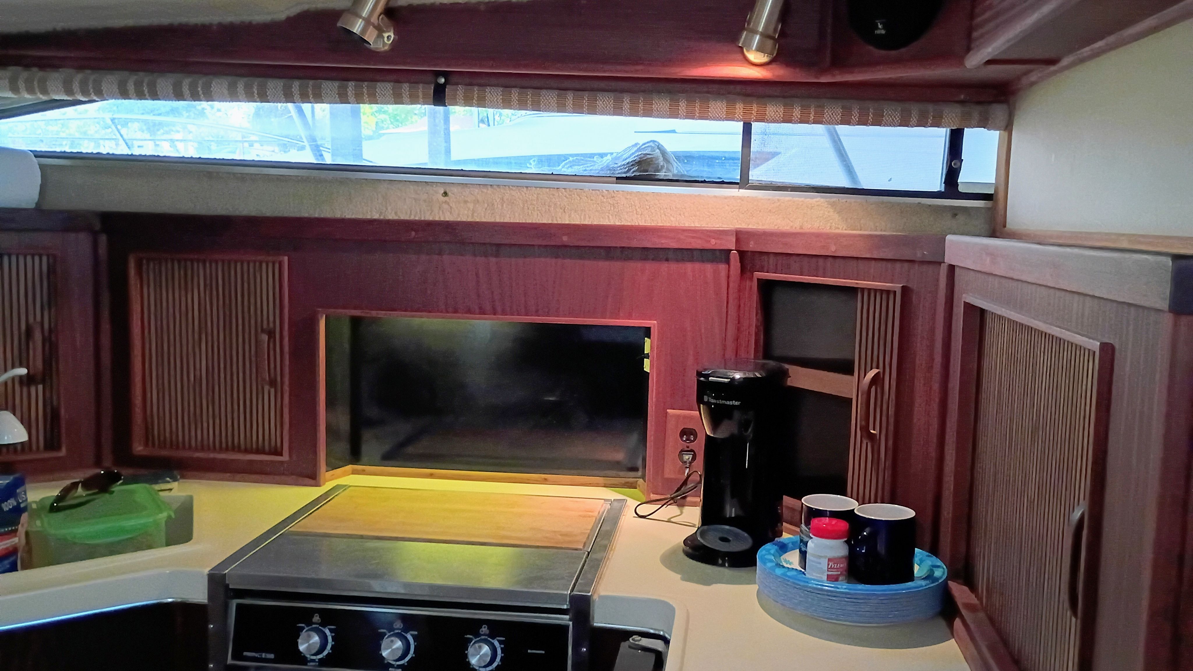 The galley of a 1986 Sea Ray Sundancer with a stove, cabinets, and a coffee maker.