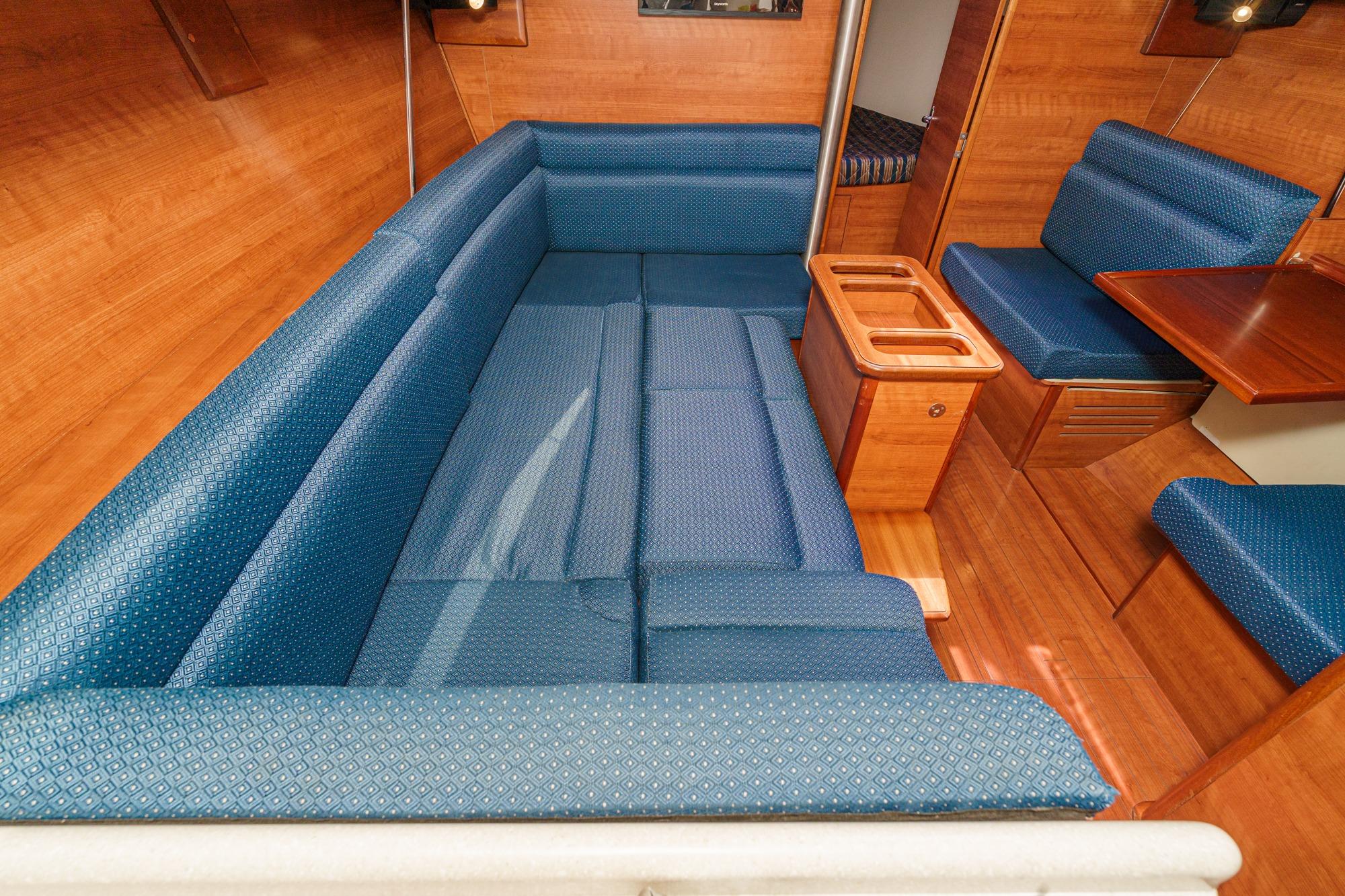 Interior of 2015 Hunter 33 sailboat with blue cushioned seating and wooden accents.