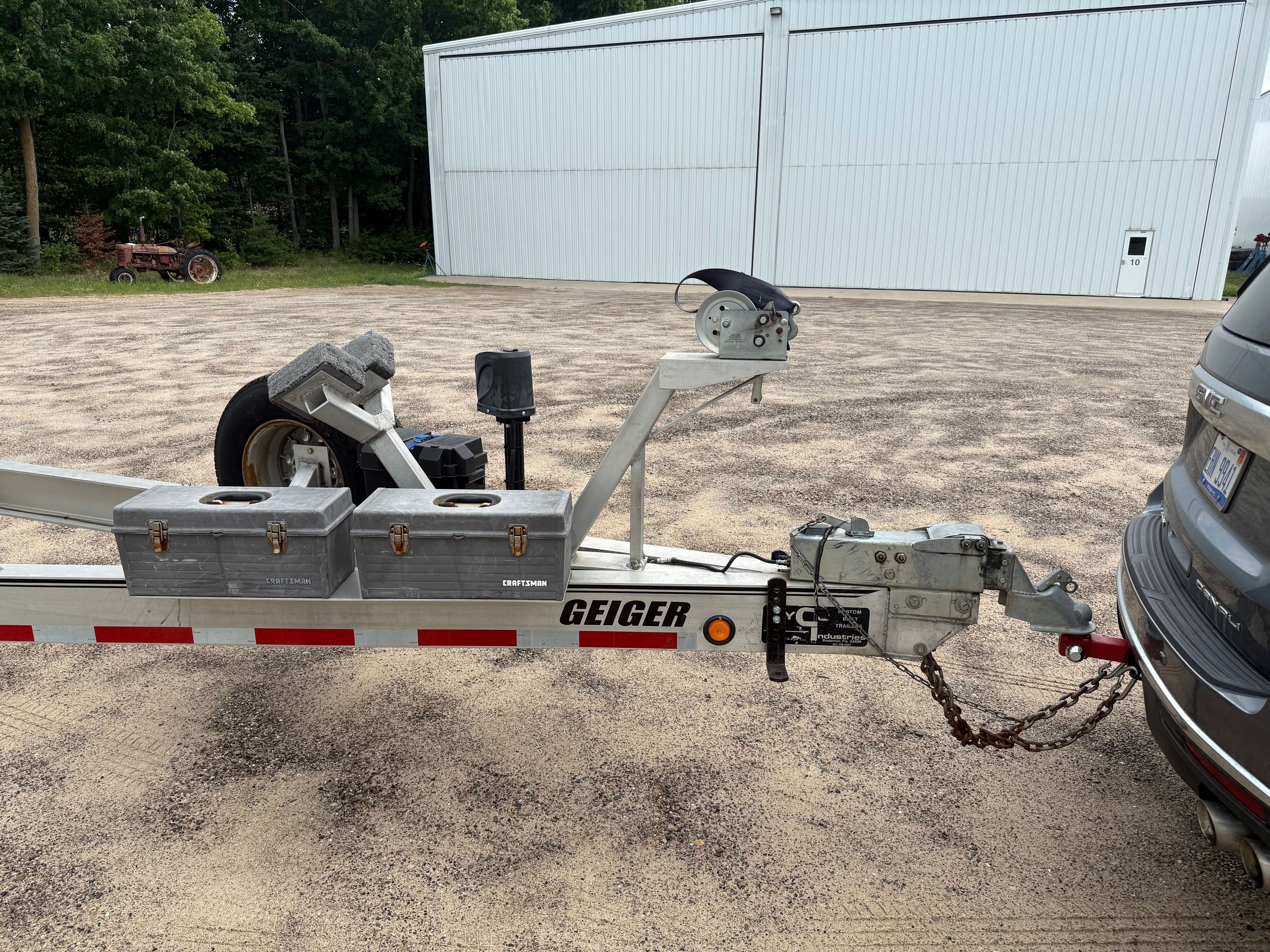 Trailer with Geiger branding, hitched to a vehicle, on a gravel lot.