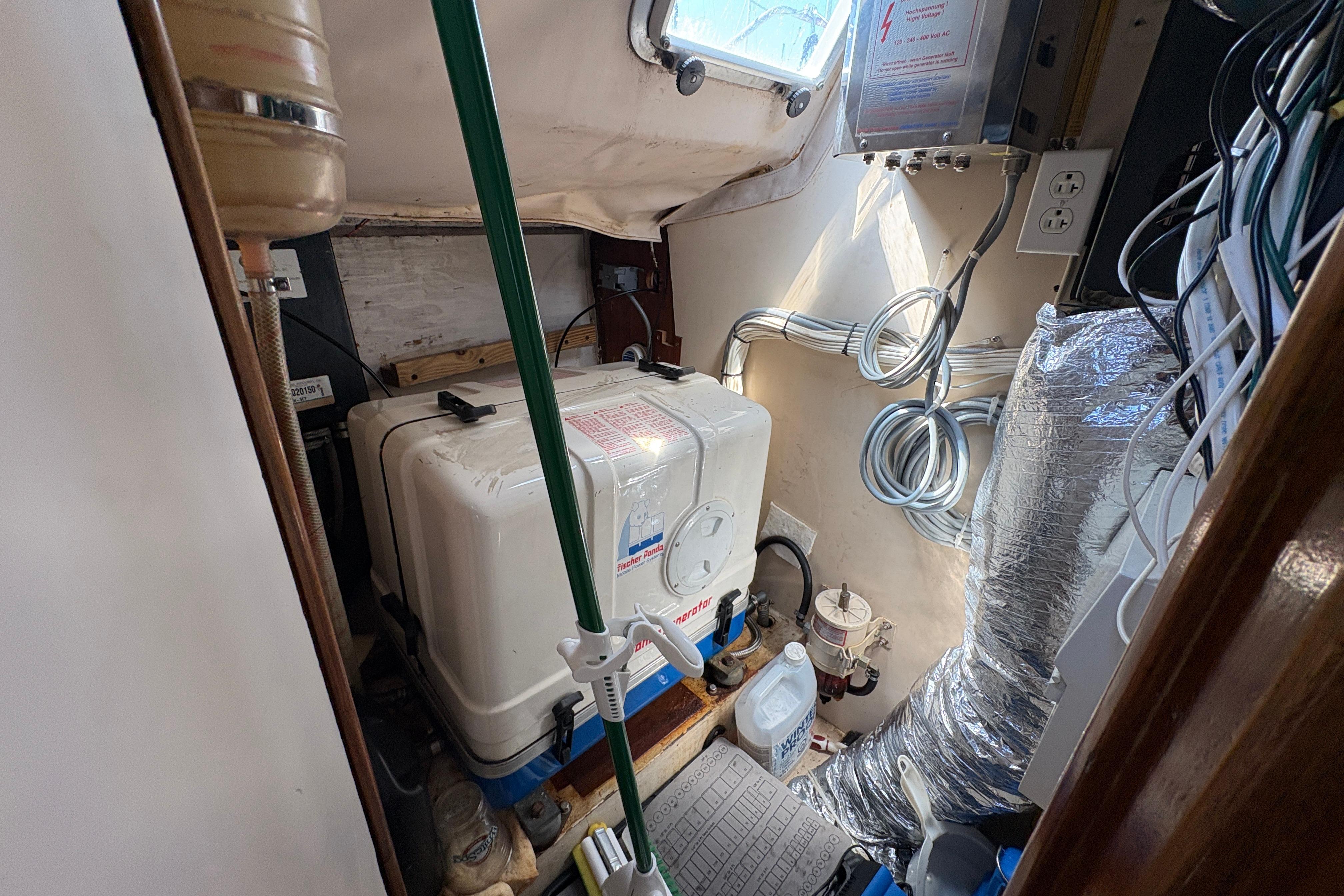 Engine room of 1990 Beneteau Oceanis 500 sailboat, featuring generator and wiring.