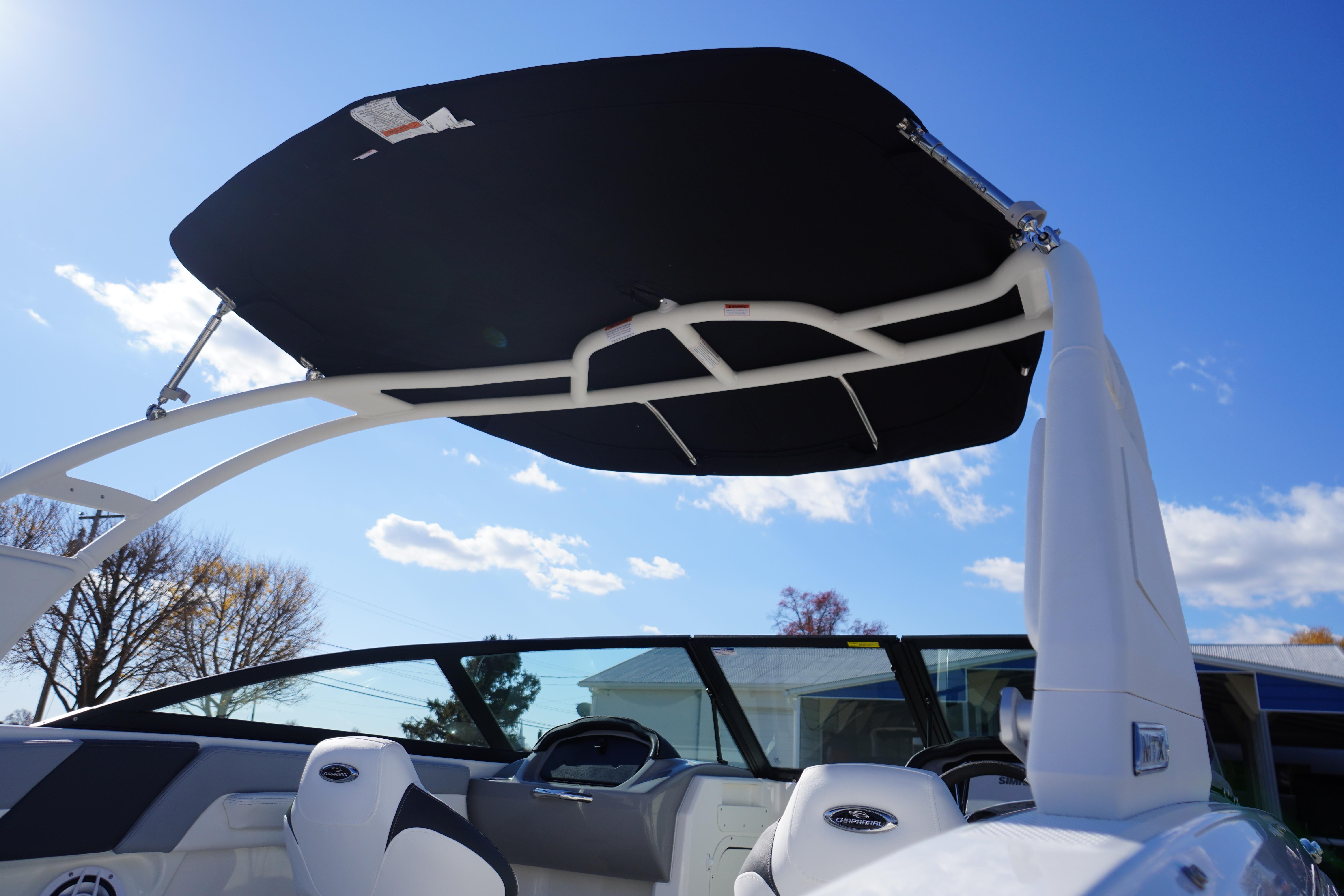 2026 Chaparral 23 SSi OB boat with sleek black canopy under clear blue sky.
