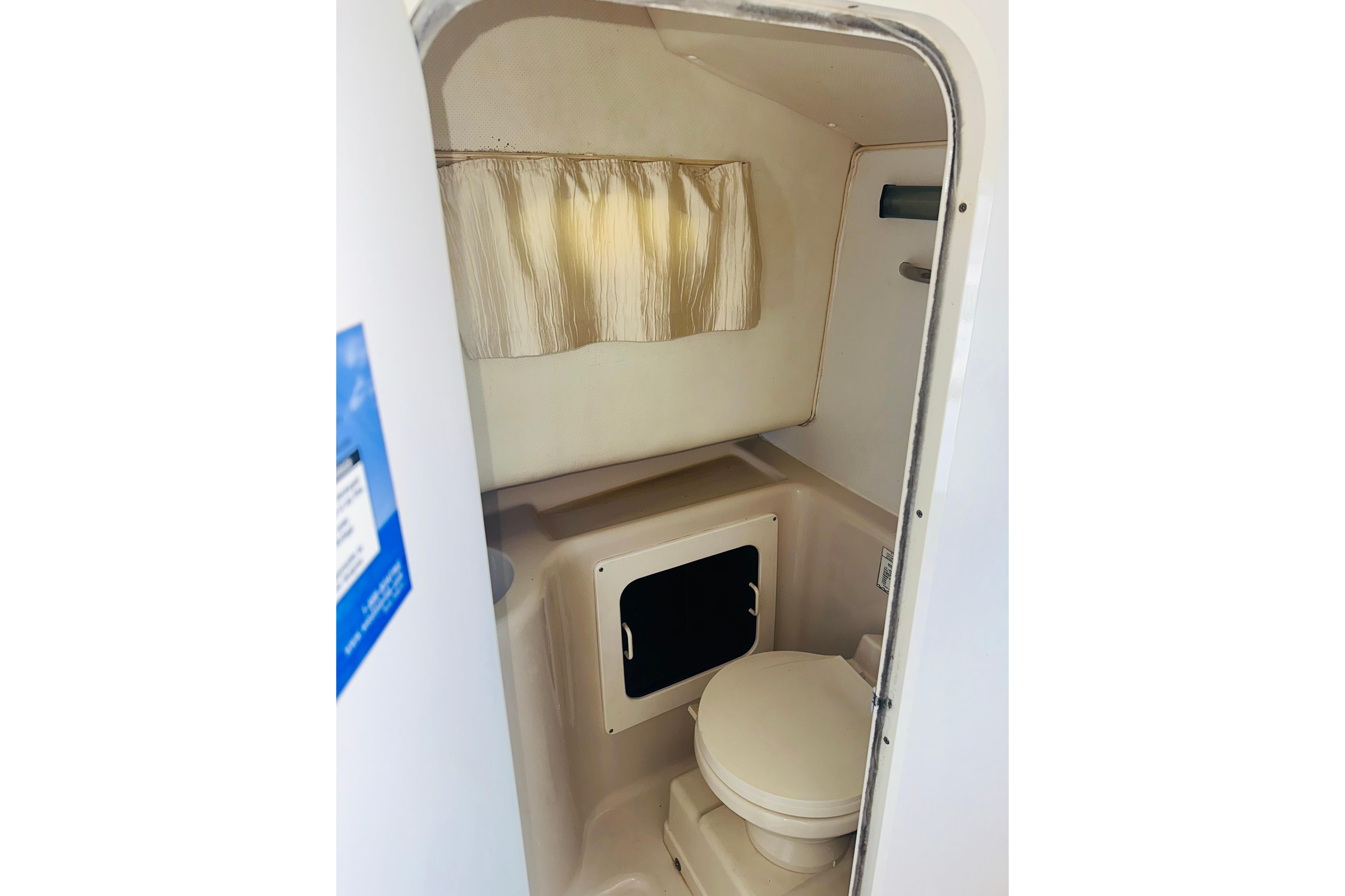 1994 Pro-Line 2950 Walkaround boat interior with compact bathroom and curtain.