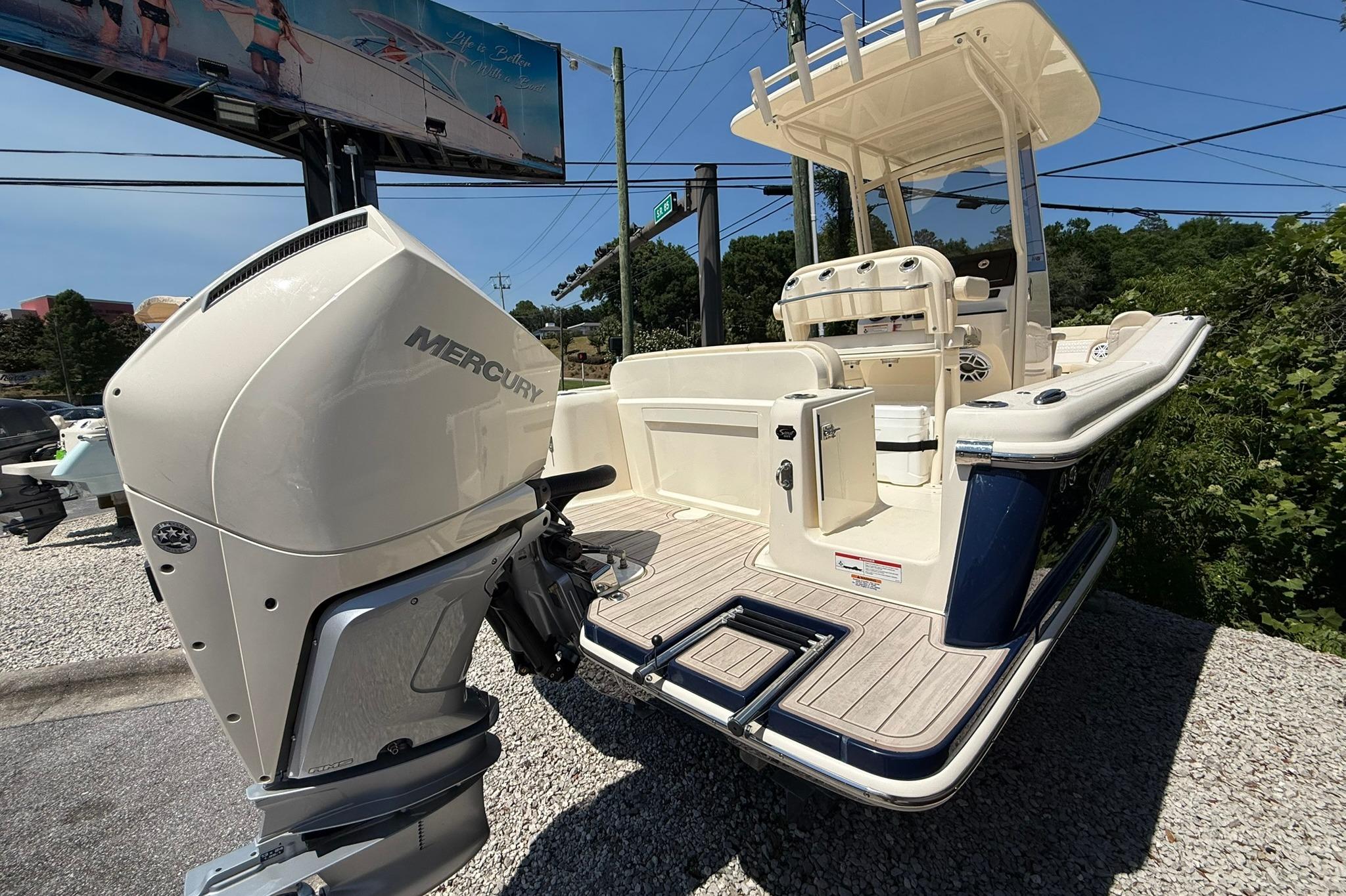 2027 Scout 240 XSF boat with Mercury outboard engine, displayed outdoors on gravel.
