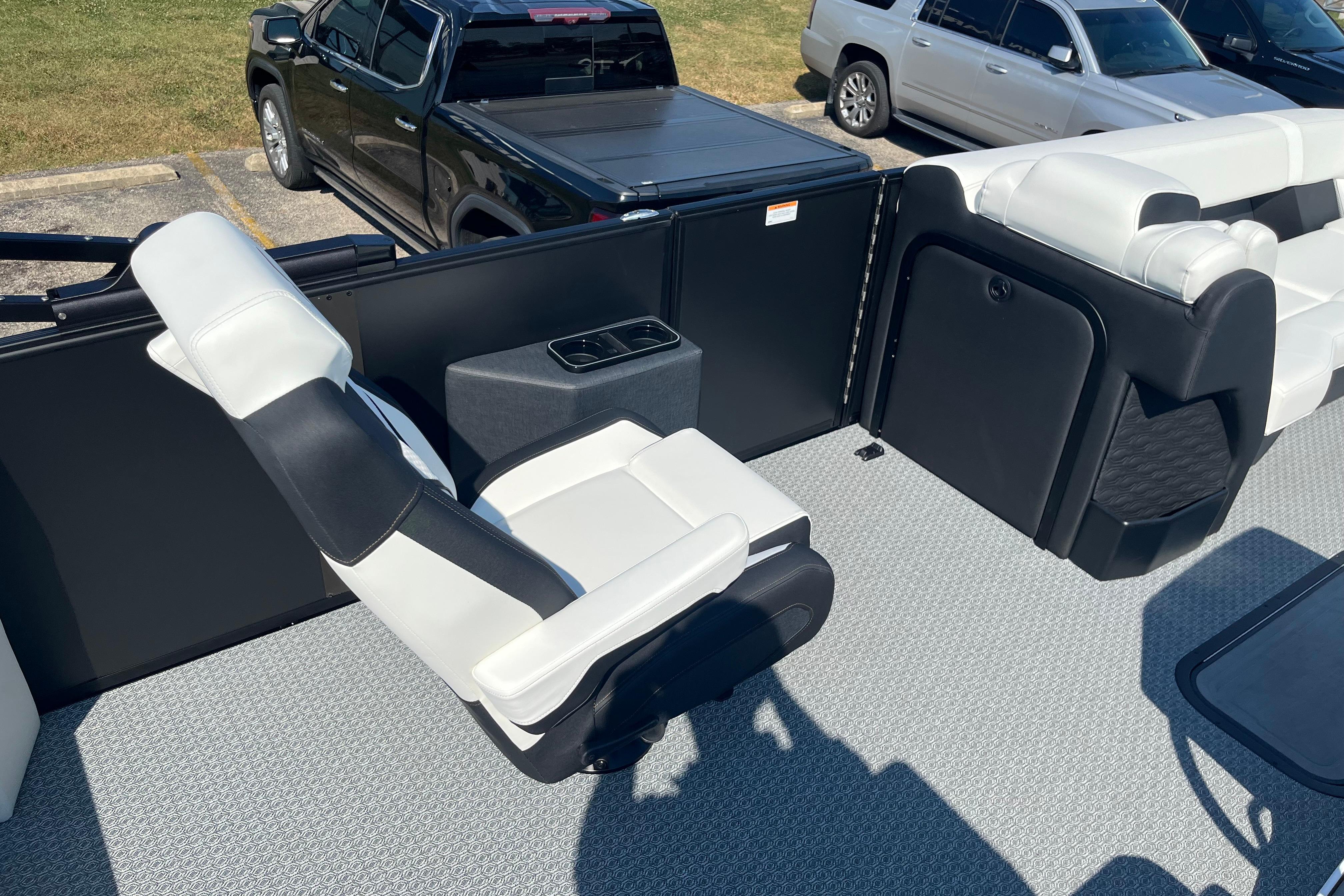 Interior of 2026 Evotti 725CS boat with white and black seating, parked vehicles visible.