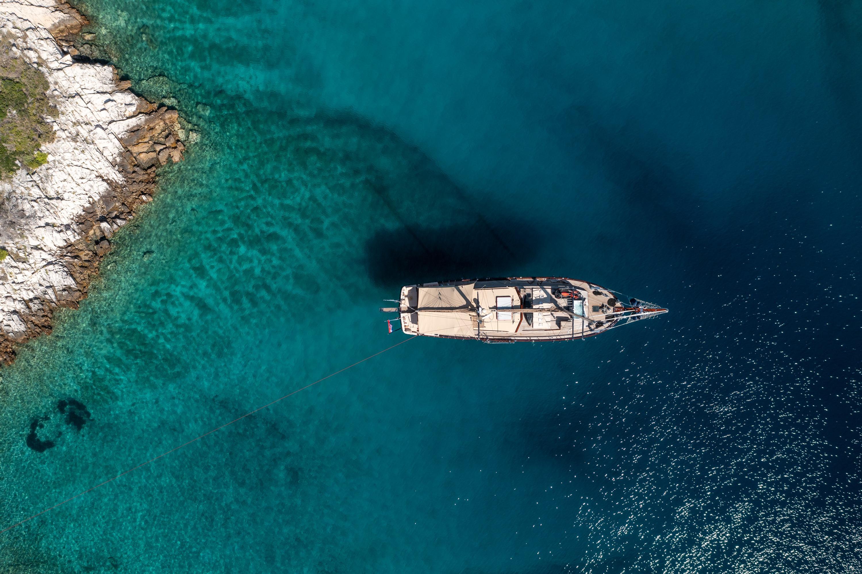 Aerial view of a 2000 Custom GULET yacht anchored in clear turquoise waters.