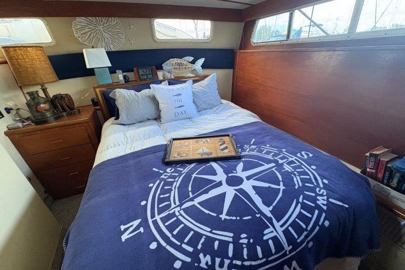 Cozy bedroom in 1987 Tollycraft 34 Sundeck Motor Yacht with nautical decor and compass-themed blanket.
