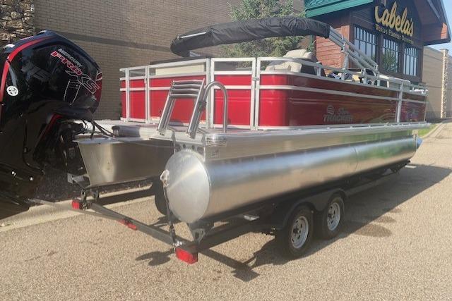 2026 Sun Tracker Fishin' Barge 22 DLX pontoon boat on trailer, parked outside Cabela's.