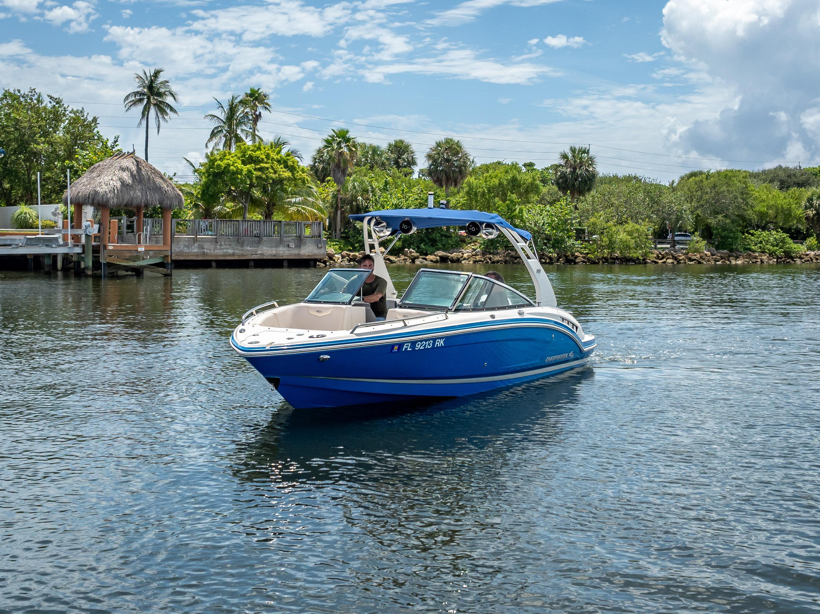 2017 Chaparral 227 SSX boat cruising on a sunny day near lush greenery.
