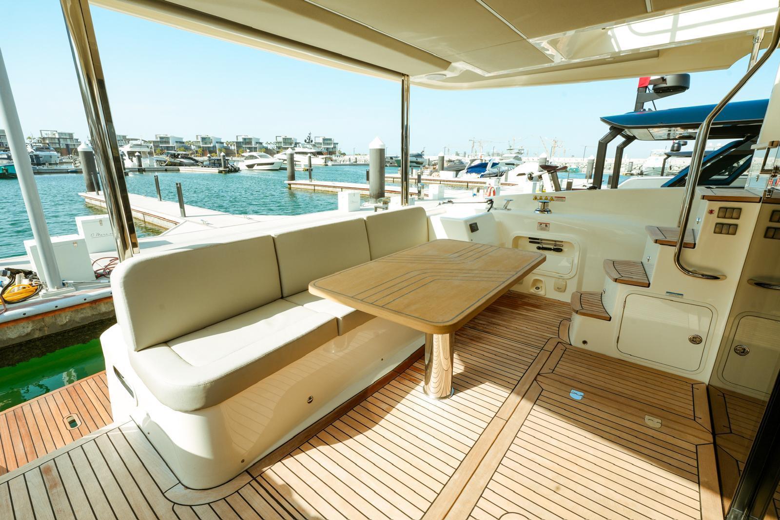 Luxurious 2024 Absolute NAVETTA 52 yacht deck with seating and table, docked at marina.