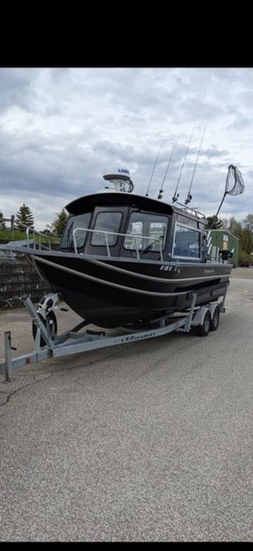 A black boat on a trailer with multiple fishing rods and a radar on the roof.