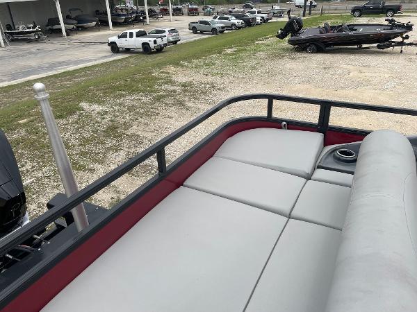 2023 Regency 250DL3 pontoon boat with spacious seating and cup holder, parked outdoors.