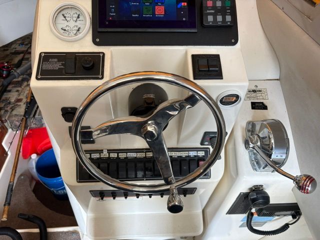 Boat helm with steering wheel, gauges, and throttle lever.