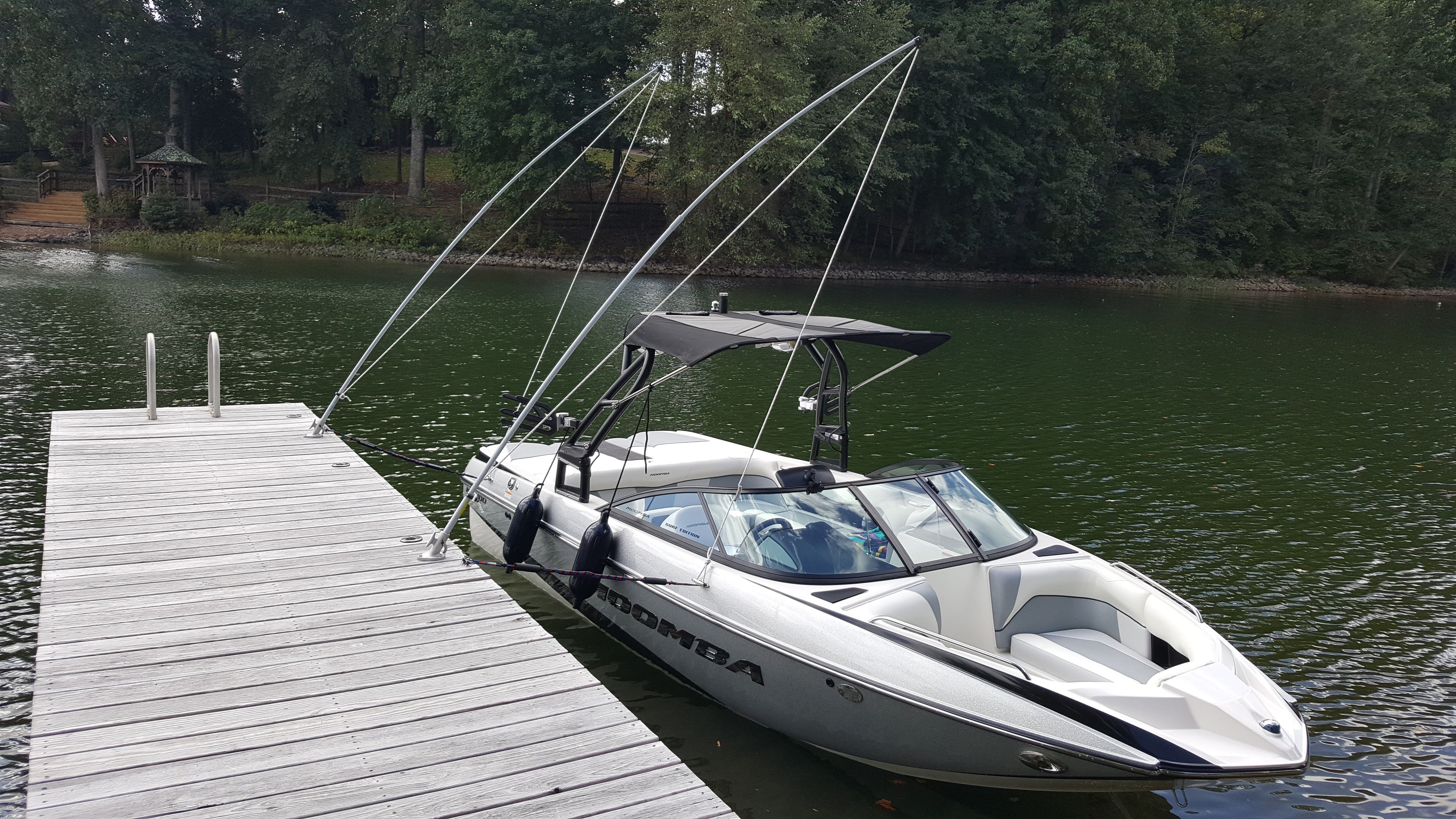 A 2016 Moomba Mondo boat docked at a wooden pier on calm, green water.