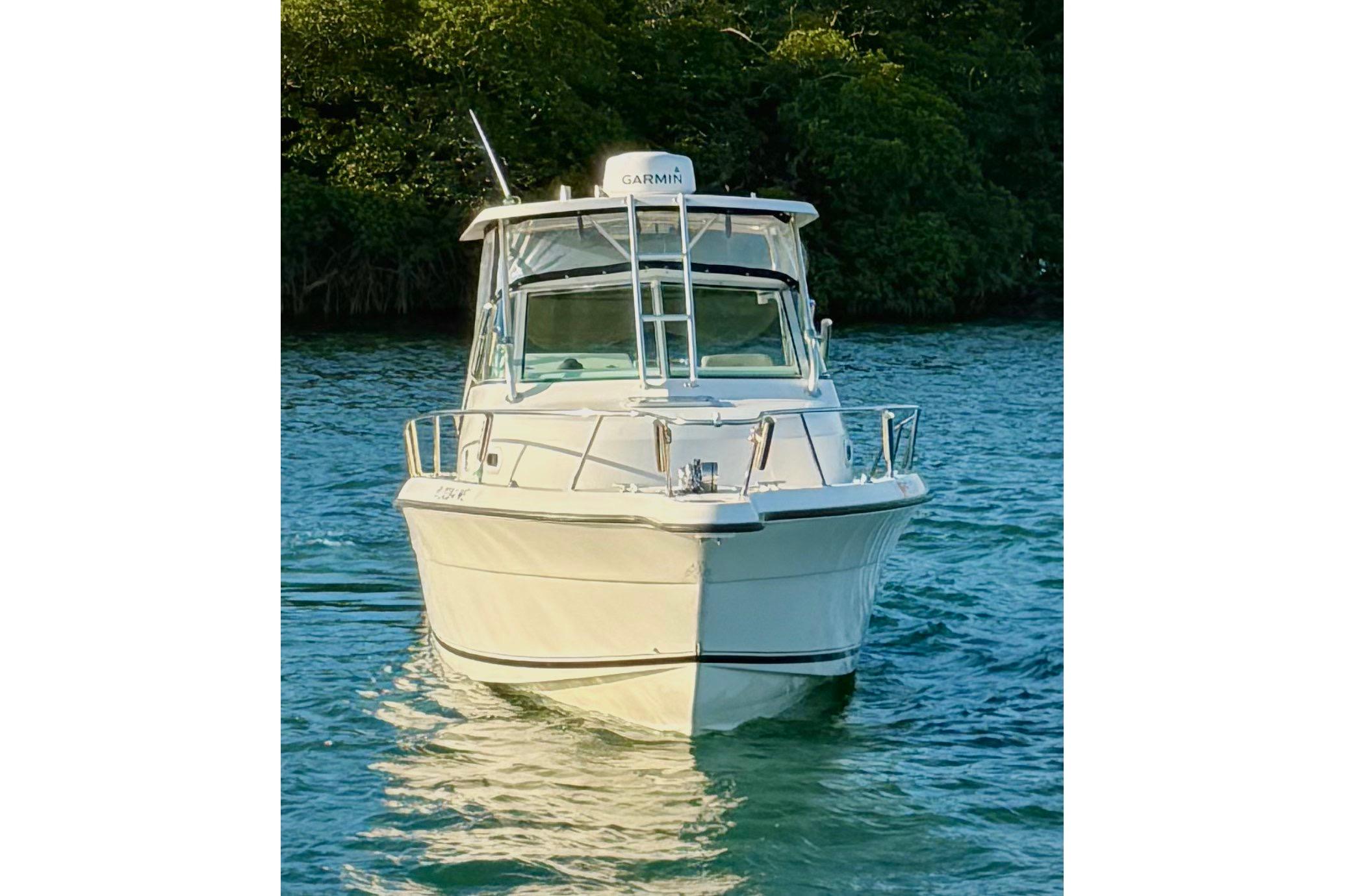 2003 Pursuit 2870 Walkaround boat on water, front view, surrounded by greenery.