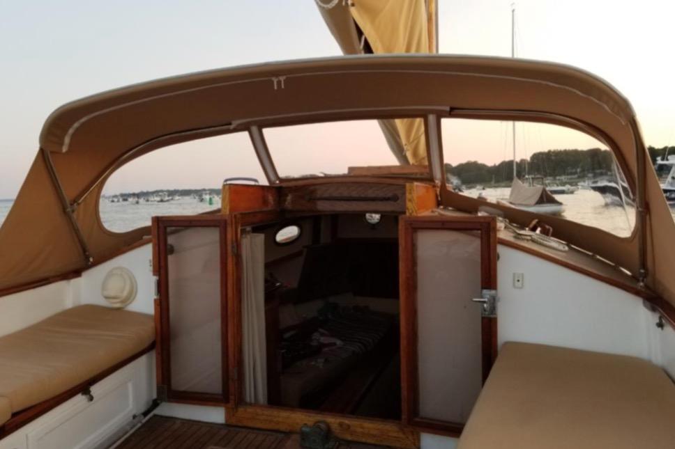 1978 Cape Cod Catboat Ted Brewer model with open cabin, docked at sunset.