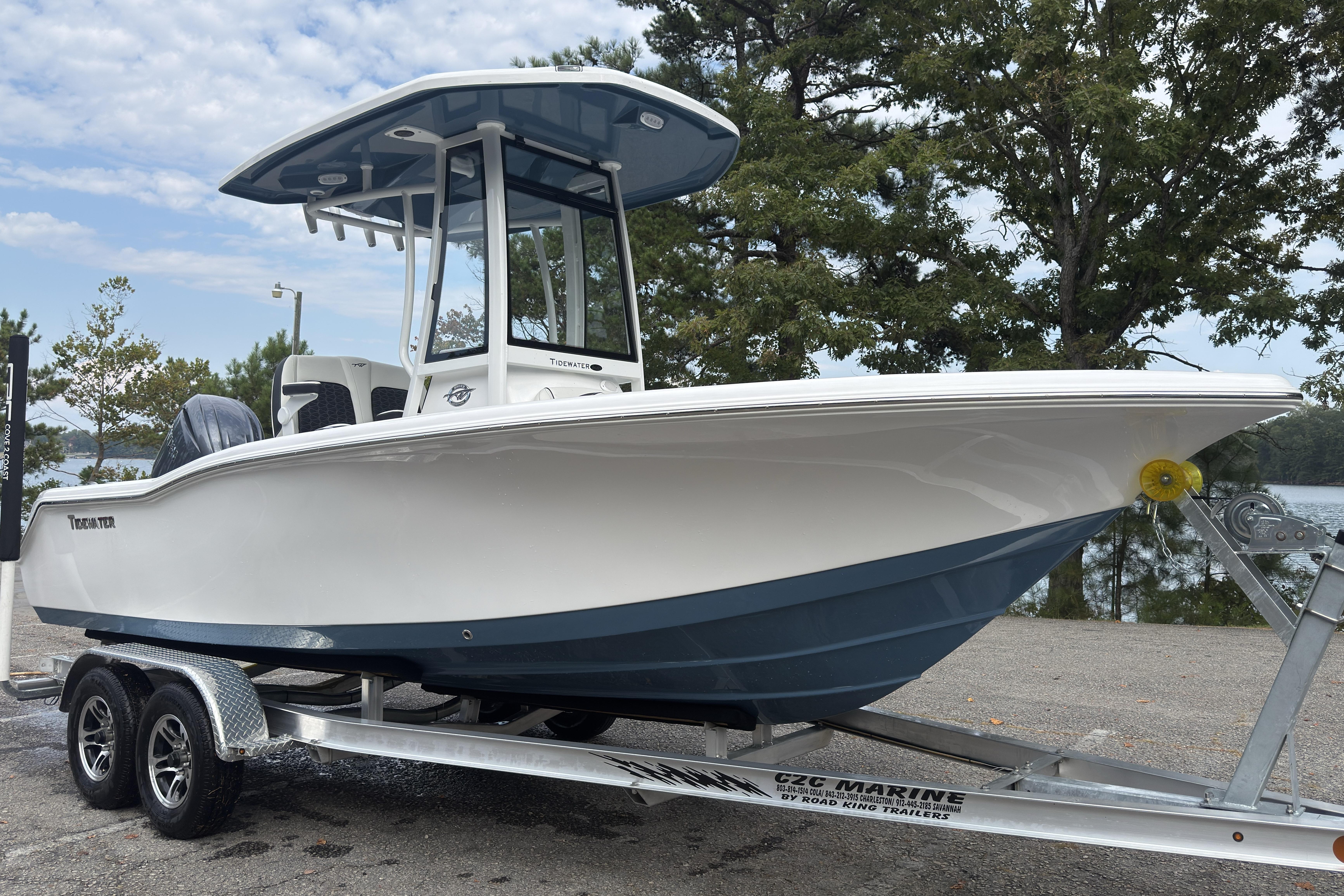 2026 Tidewater 210 CC Adventure boat on trailer, parked near trees and water.