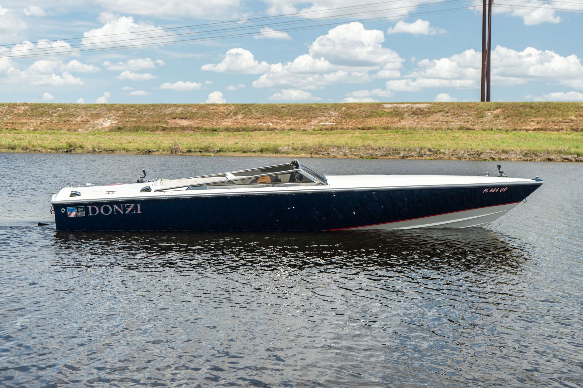 A Donzi 22 Classic boat on calm water under a blue sky.