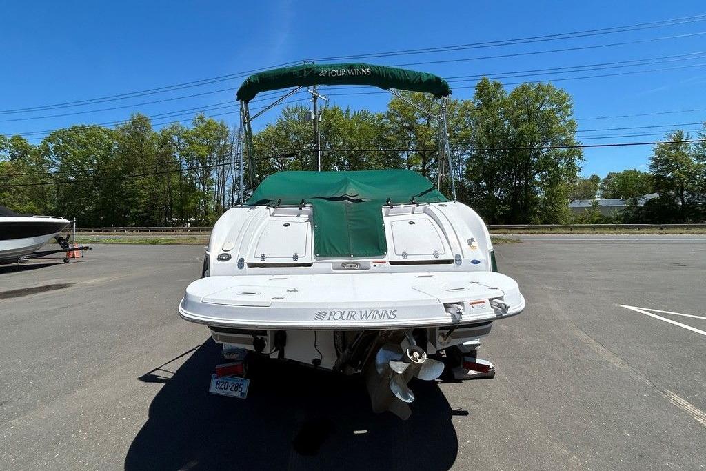 2006 Four Winns 244 Funship boat with green cover, parked outdoors on a sunny day.