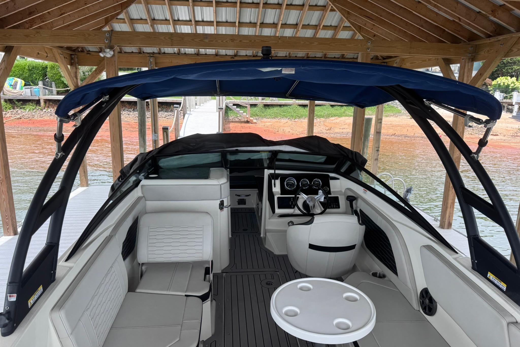 2021 Sea Ray SPX 230 boat interior with seating and dashboard under a dock canopy.