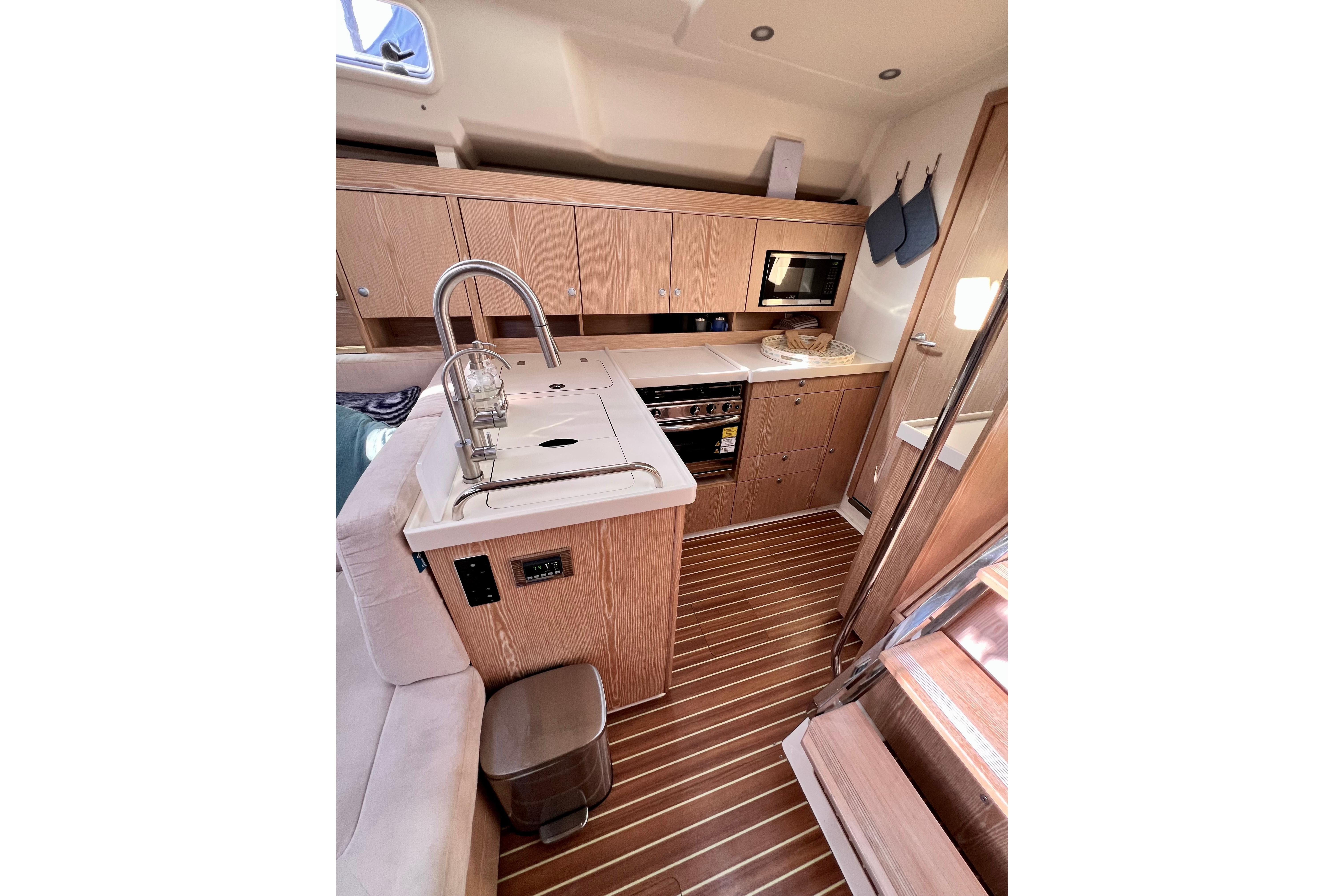 Modern kitchen interior of 2016 Hanse 455 yacht with wood finish and appliances.