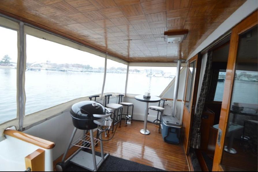 1974 Pacemaker Cockpit Motoryacht interior with seating, table, and grill overlooking water.