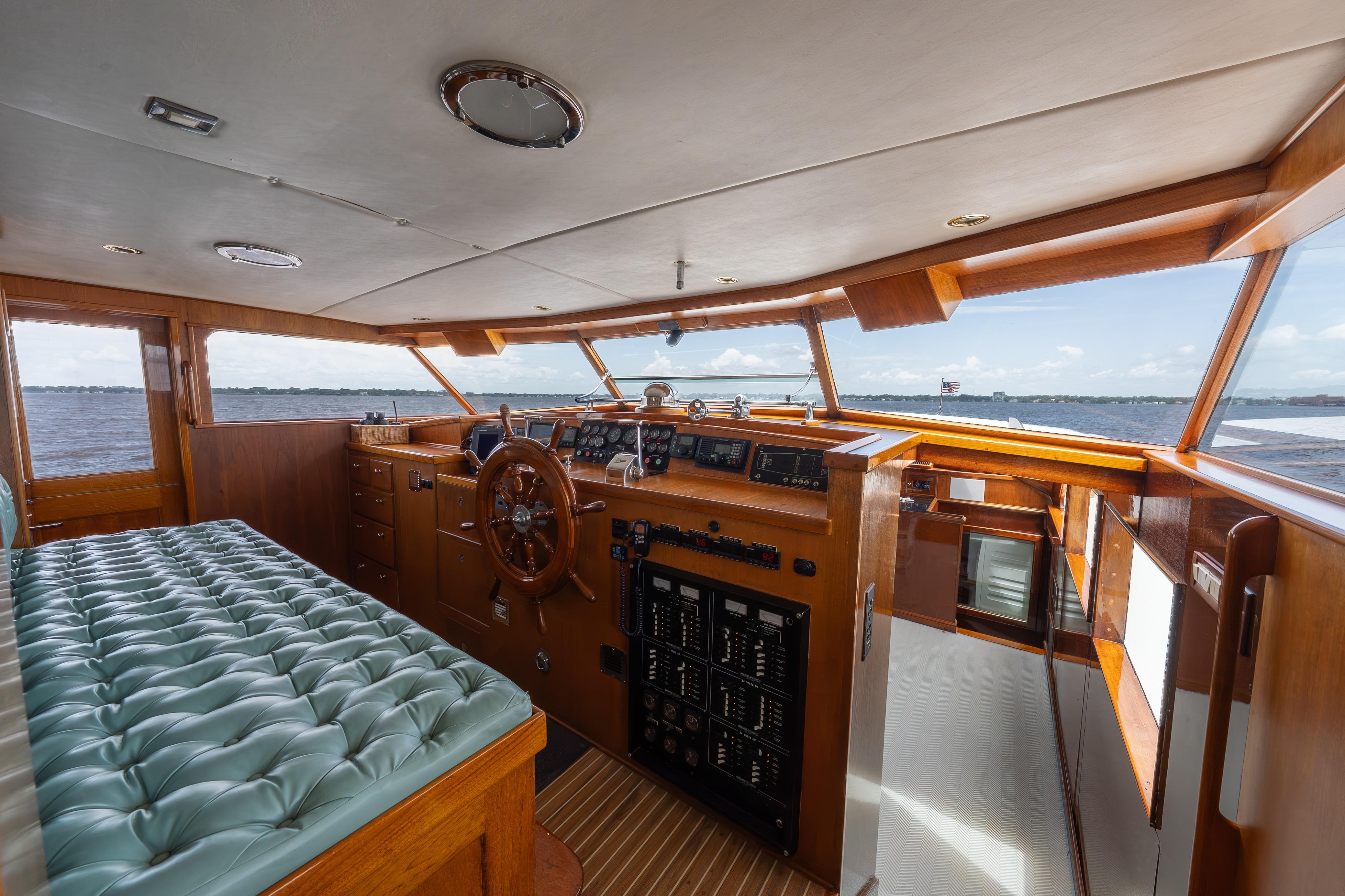 Interior of a 1963 Trumpy Classic yacht with vintage wooden helm and plush seating.