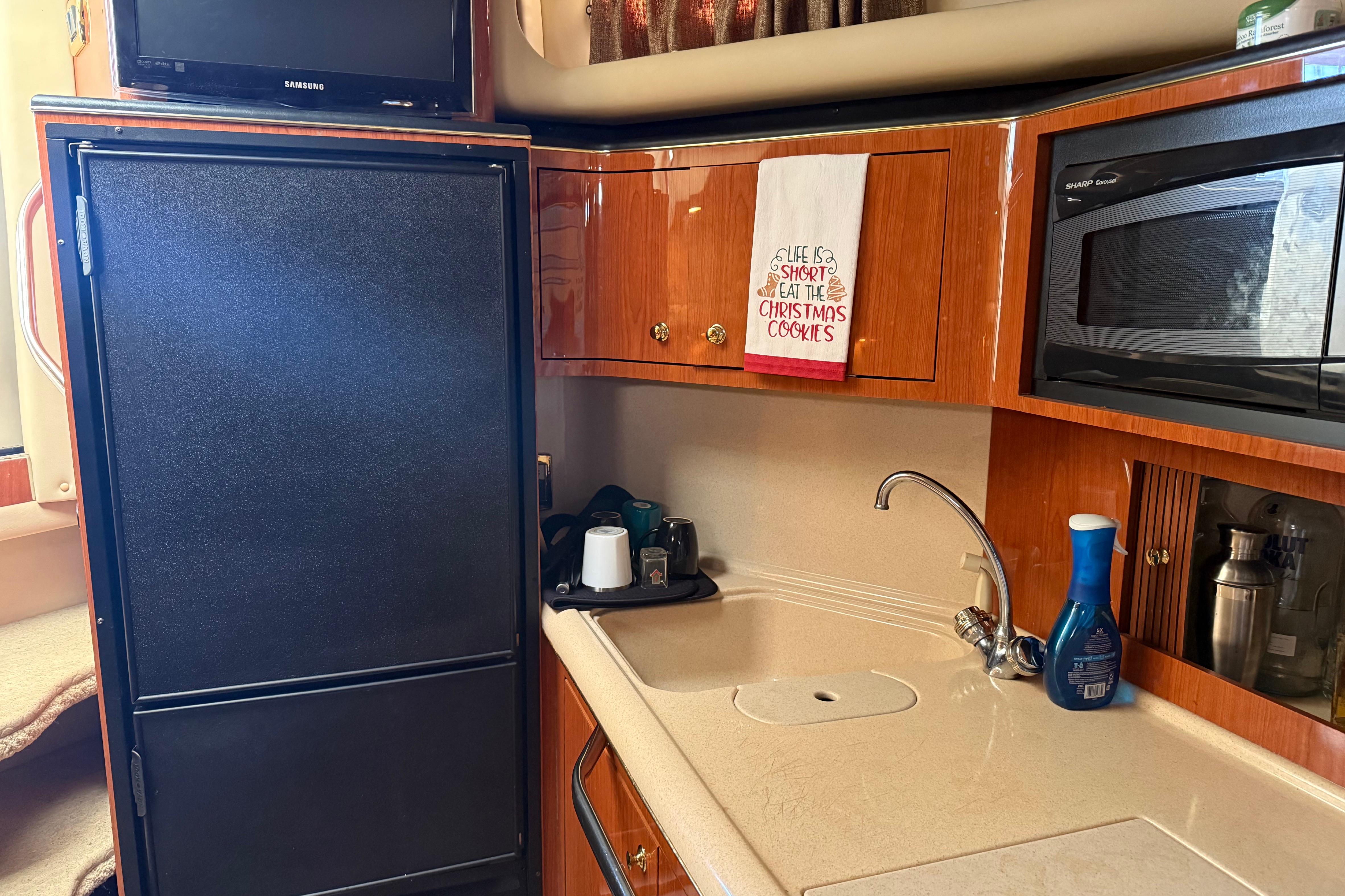 2001 Sea Ray 380 Sundancer kitchen with fridge, microwave, and sink.