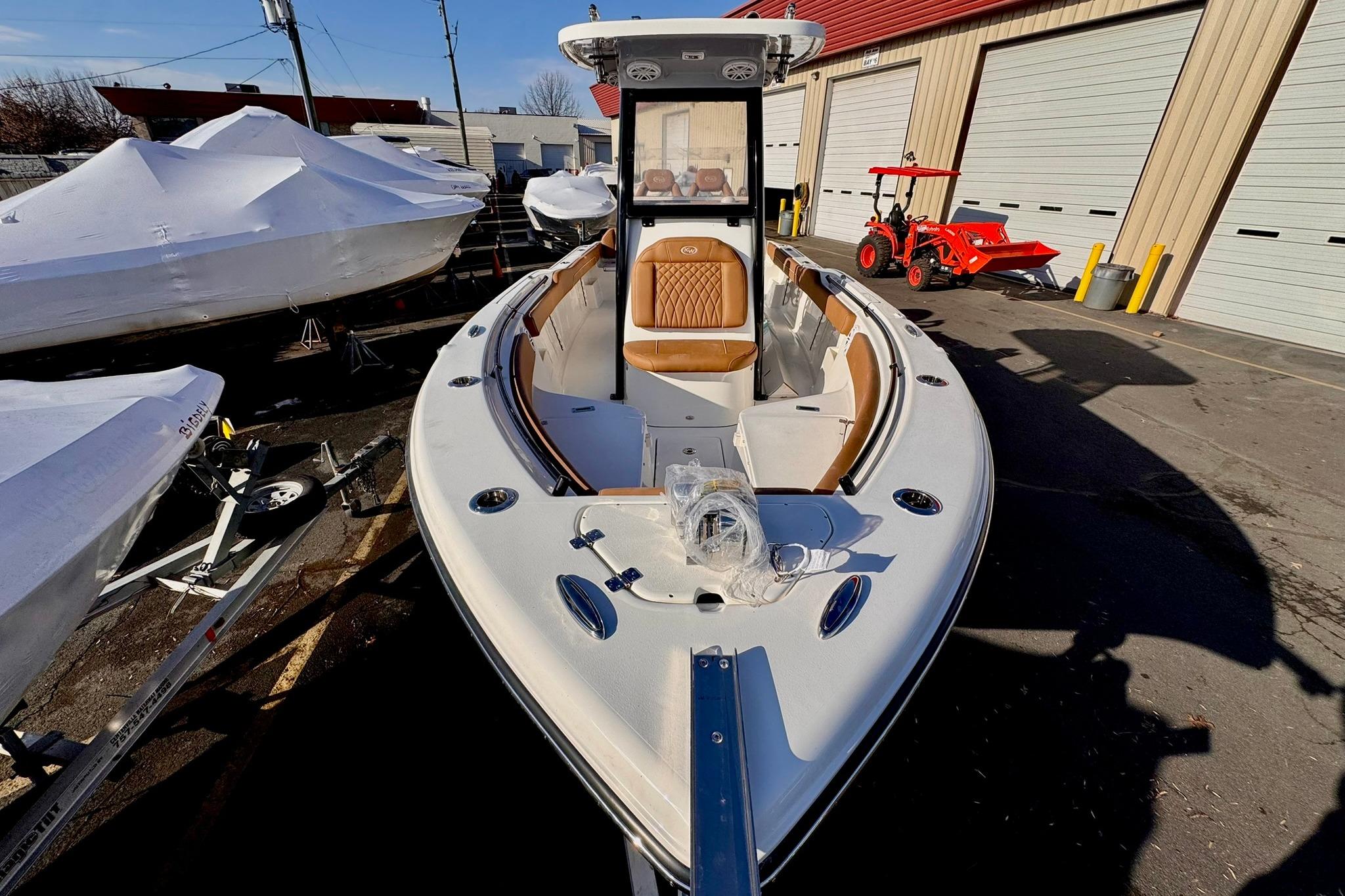 2026 Key West 239 FSR boat with tan seating, parked outdoors near storage units.