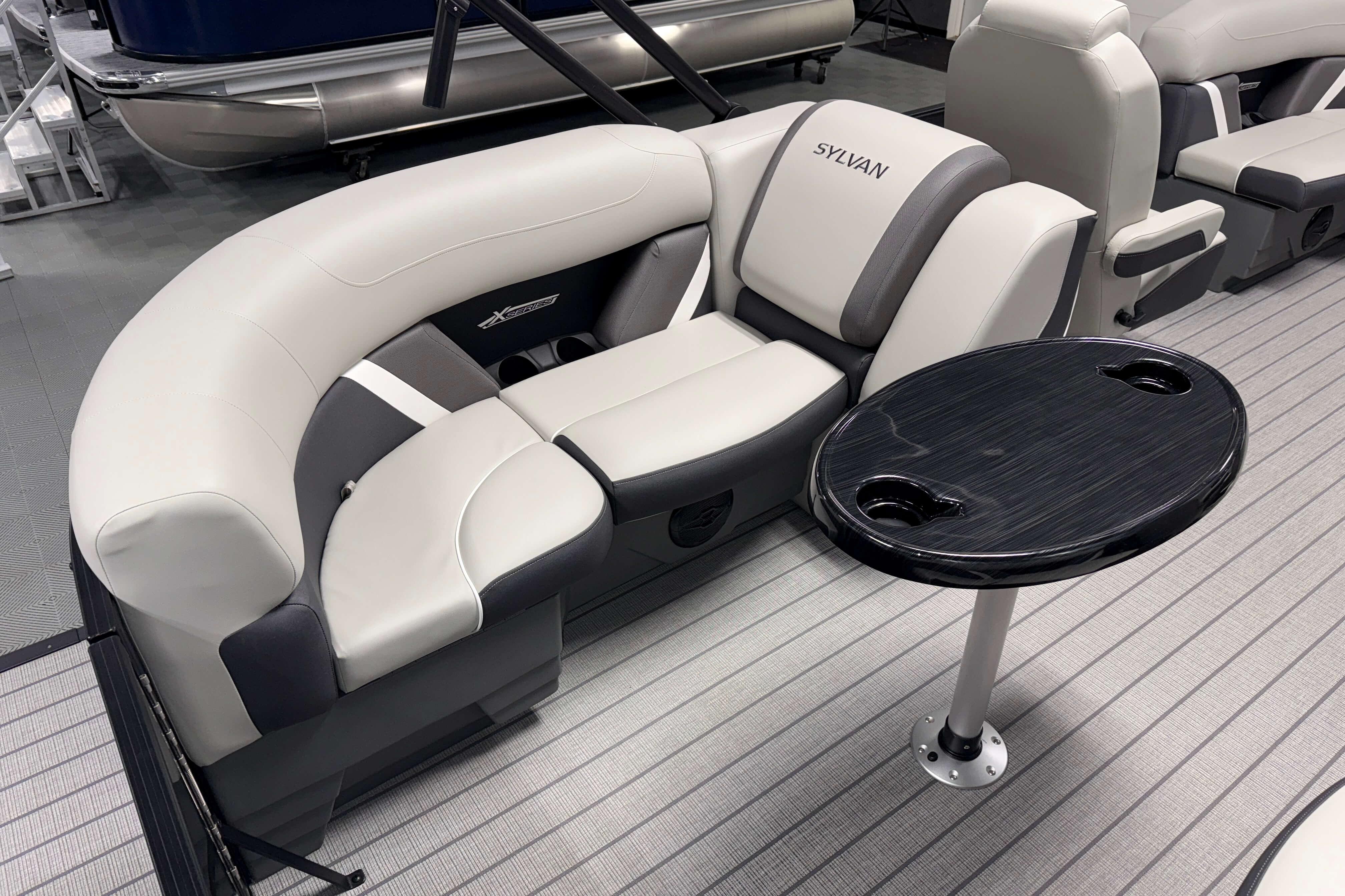 Luxurious seating on 2026 Sylvan Mirage X1 pontoon boat with sleek table design.