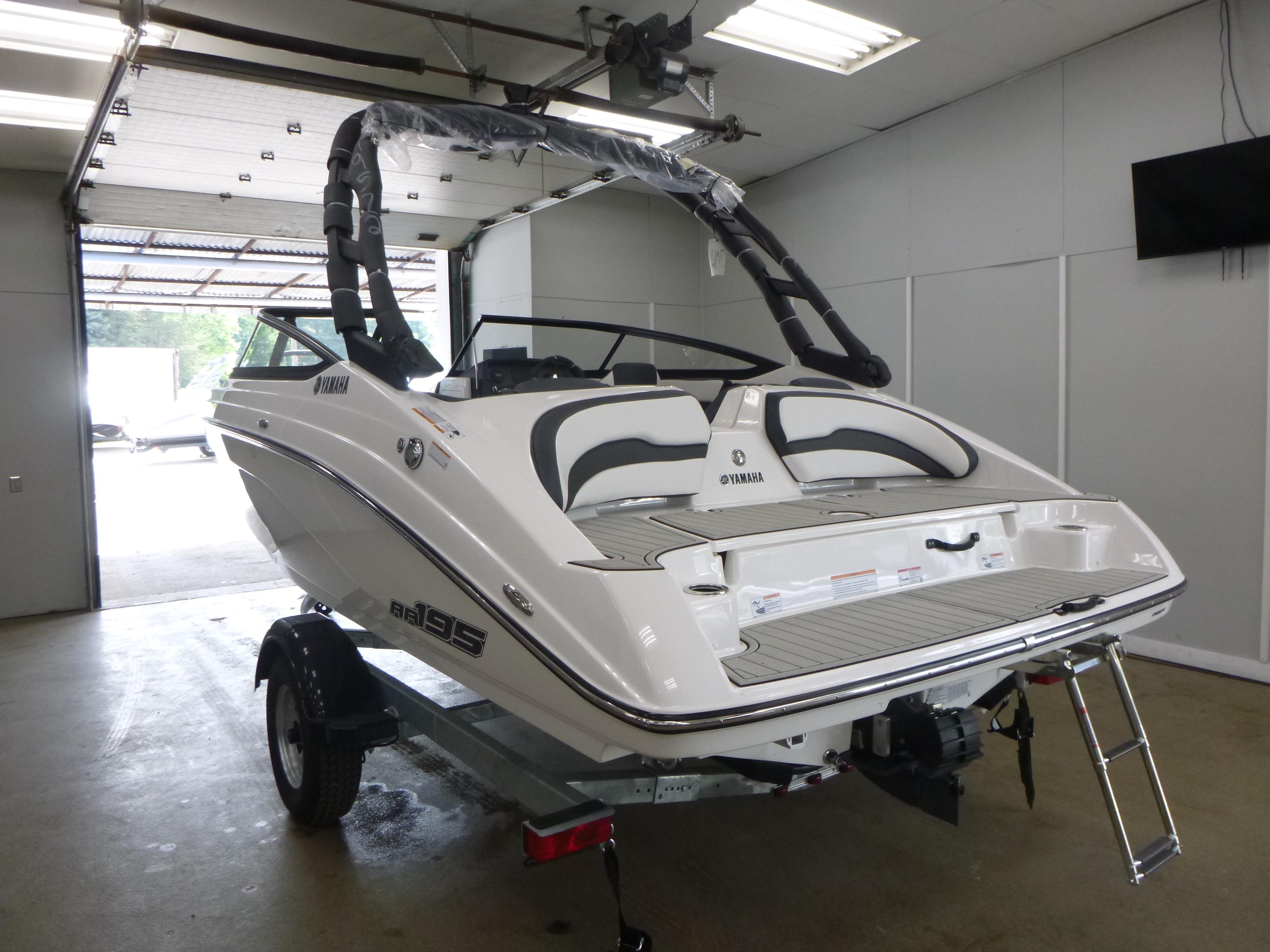 2025 Yamaha Boats AR195 in showroom, rear view with swim platform and ladder.