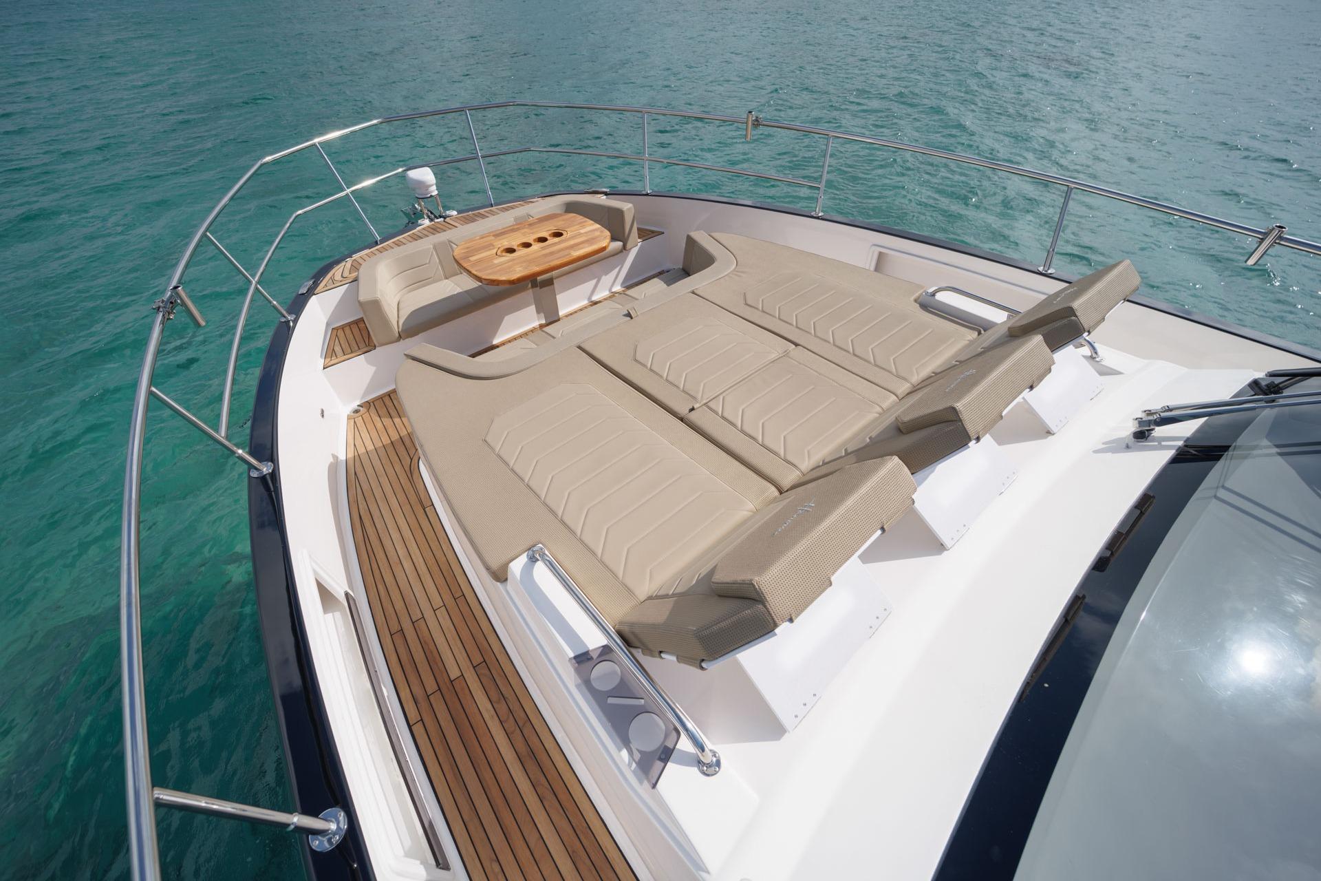 Luxurious Hanover 447 yacht deck with sun loungers and table, 2026 model, on clear blue water.
