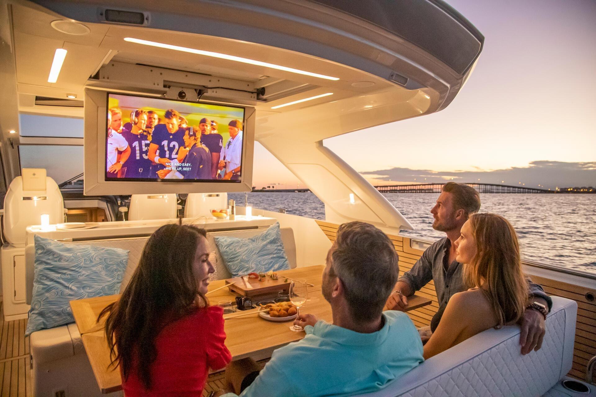 Four people enjoying a movie on a Jeanneau DB/43 OB yacht at sunset.