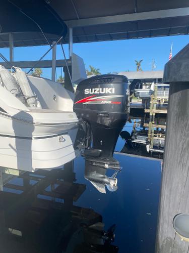 2015 Hurricane SunDeck 2400 OB with Suzuki outboard motor docked by water.