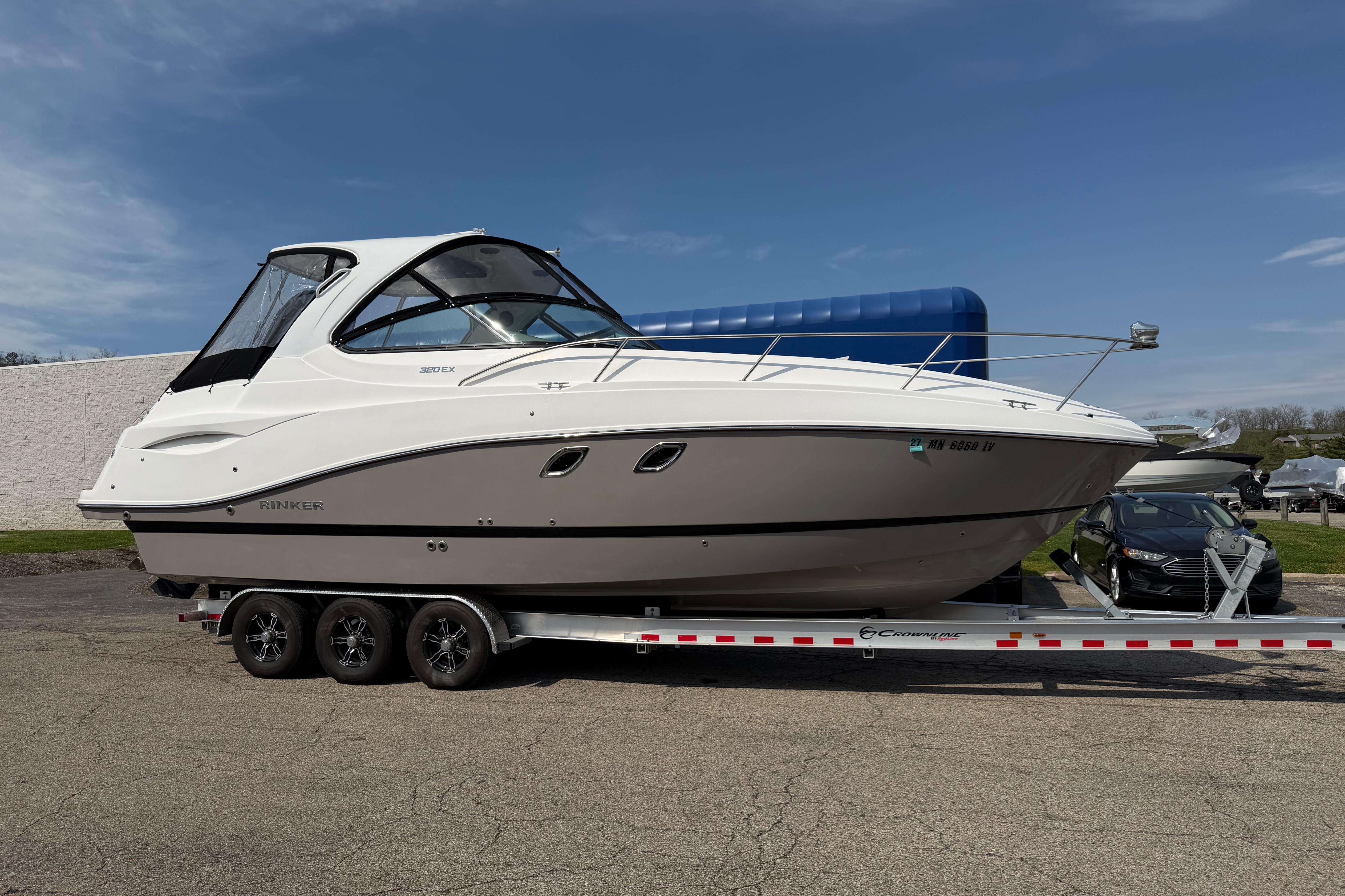 2019 Rinker EX 320 boat on trailer, parked outdoors under clear sky.