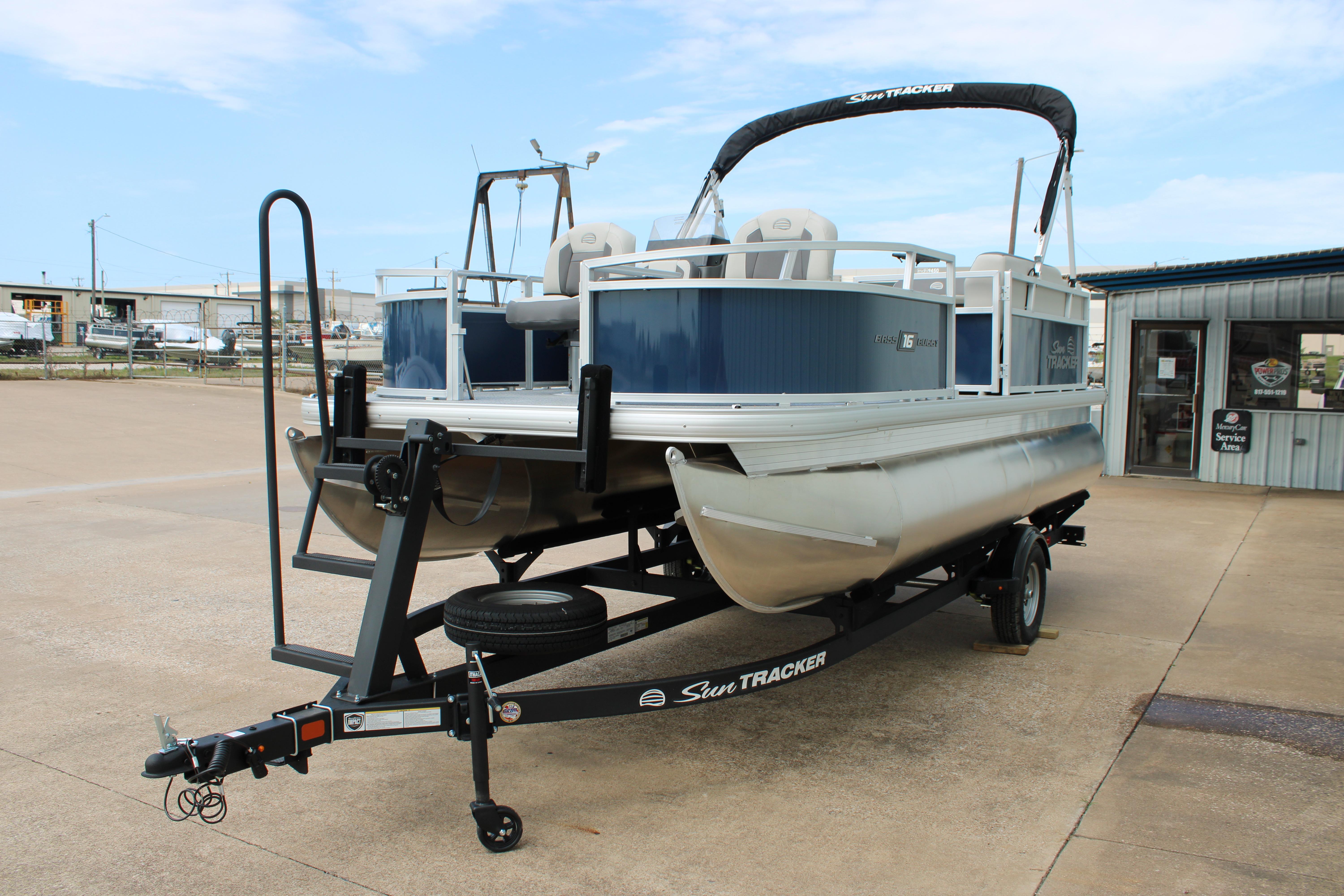 2026 Sun Tracker Bass Buggy 16 XL Select pontoon boat on trailer, parked outdoors.