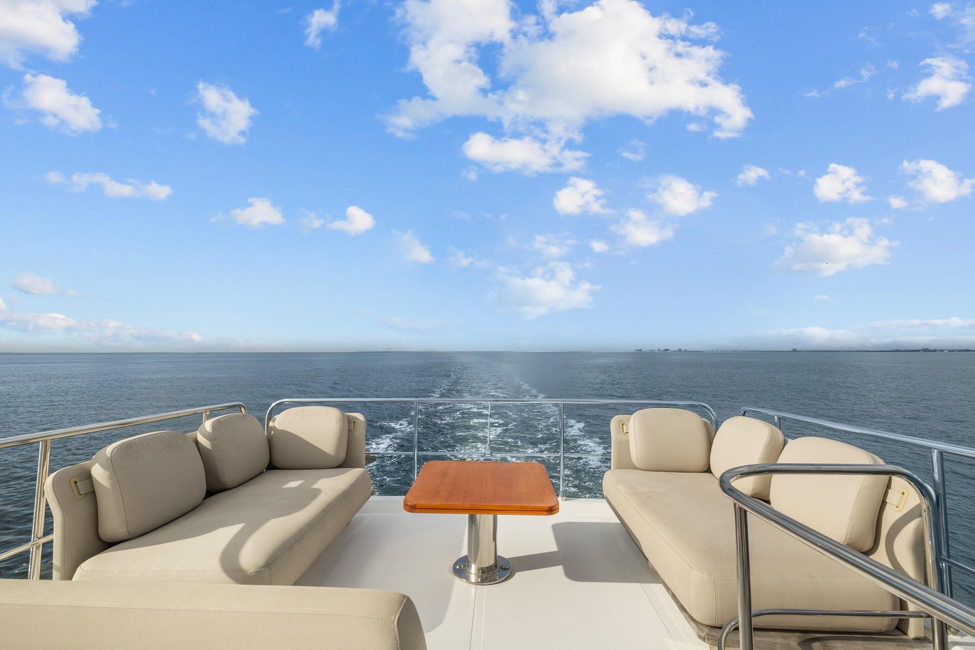 Luxurious 2019 Azimut 55 yacht deck with plush seating, ocean view, and clear blue sky.