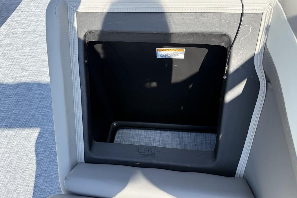 2026 Premier 220 Sunscape RF storage compartment with warning label, featuring gray upholstery.