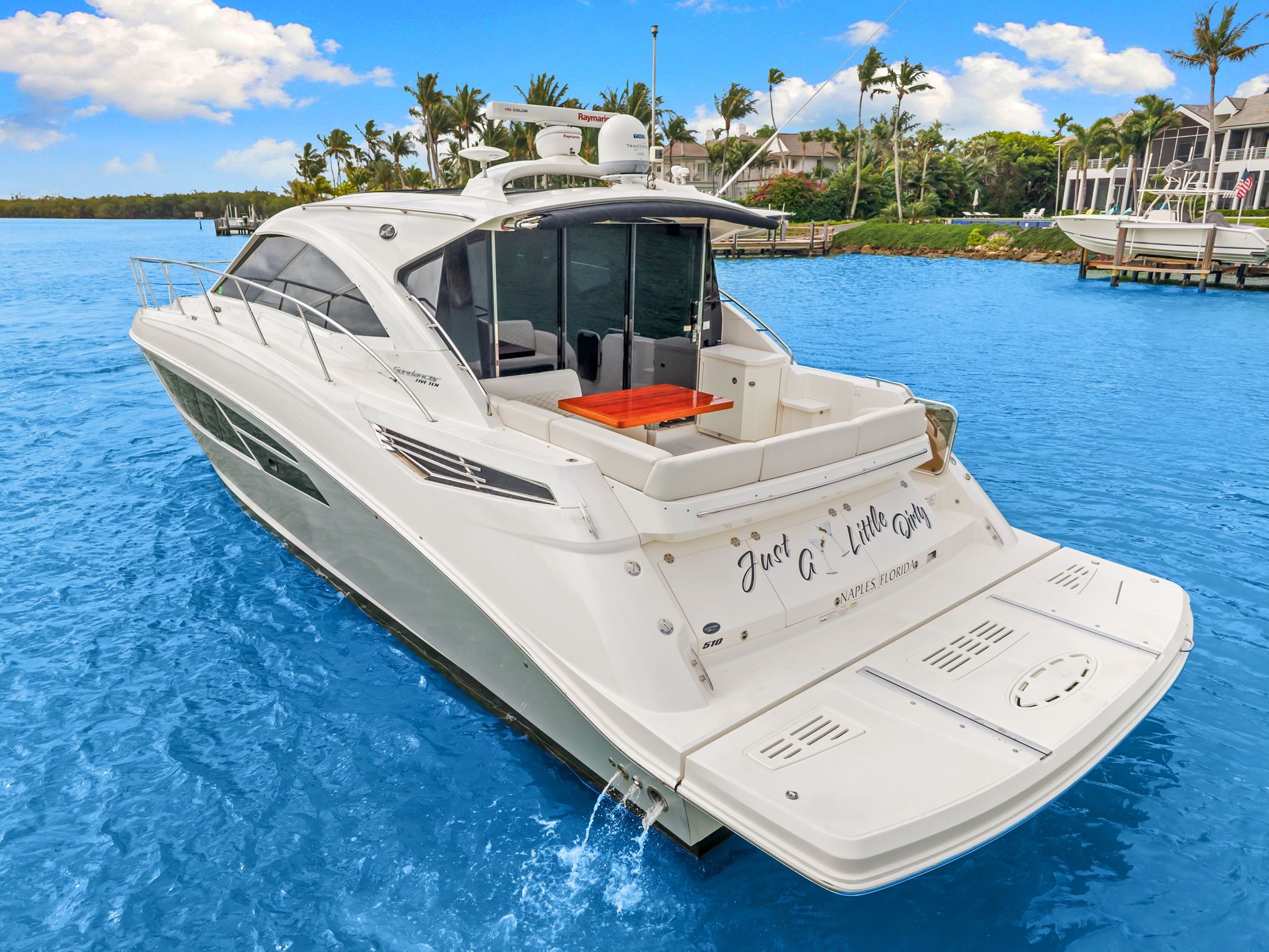 A 2017 Sea Ray Sundancer 510 on blue water with palm trees in the background.