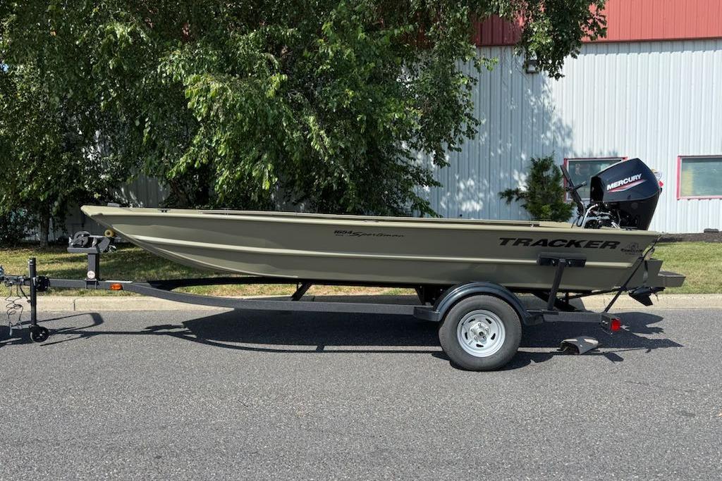 2026 Tracker Grizzly 1654 T Sportsman boat on trailer, parked outdoors.