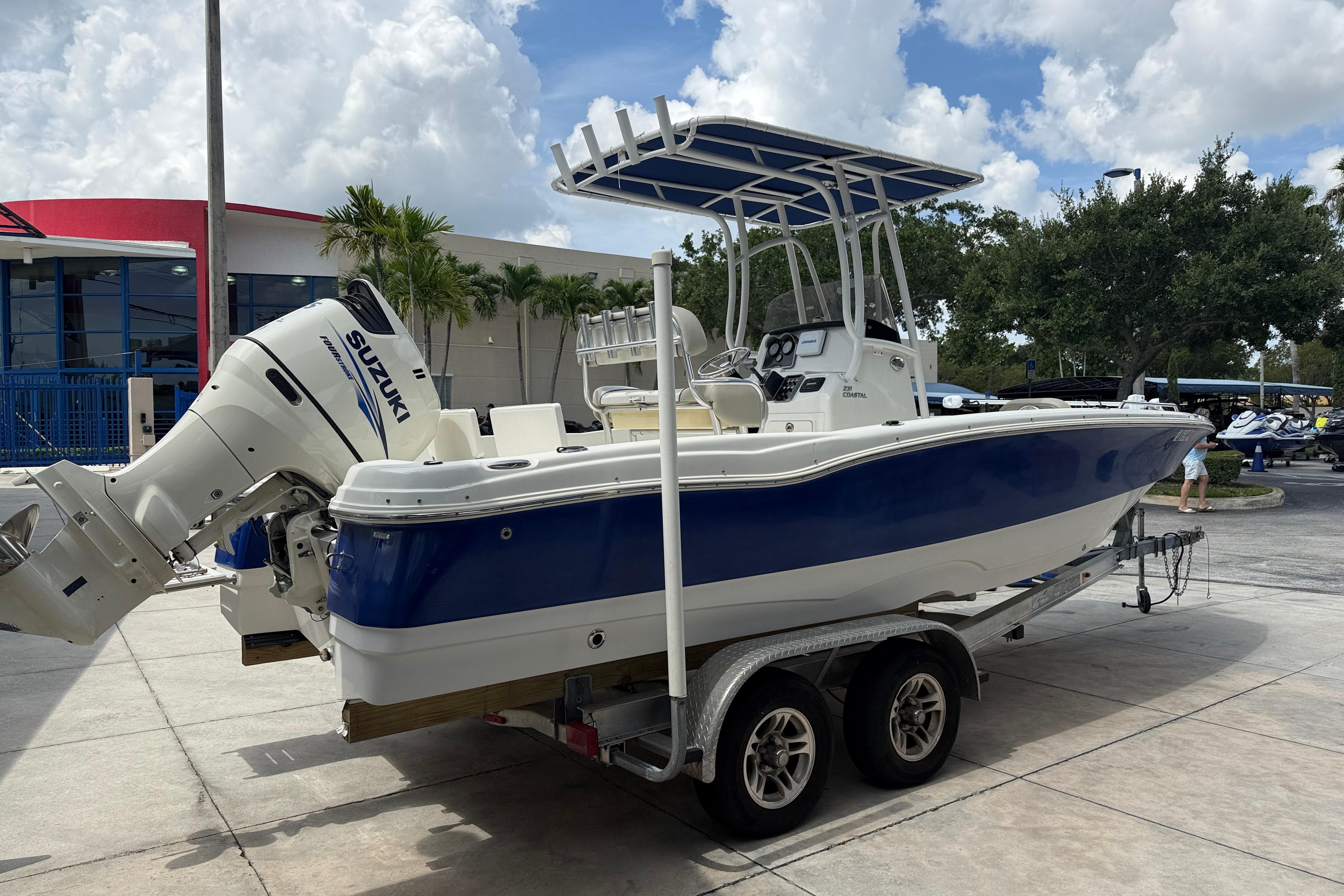 2015 NauticStar 231 Coastal boat with Suzuki engine on a trailer, parked outdoors.