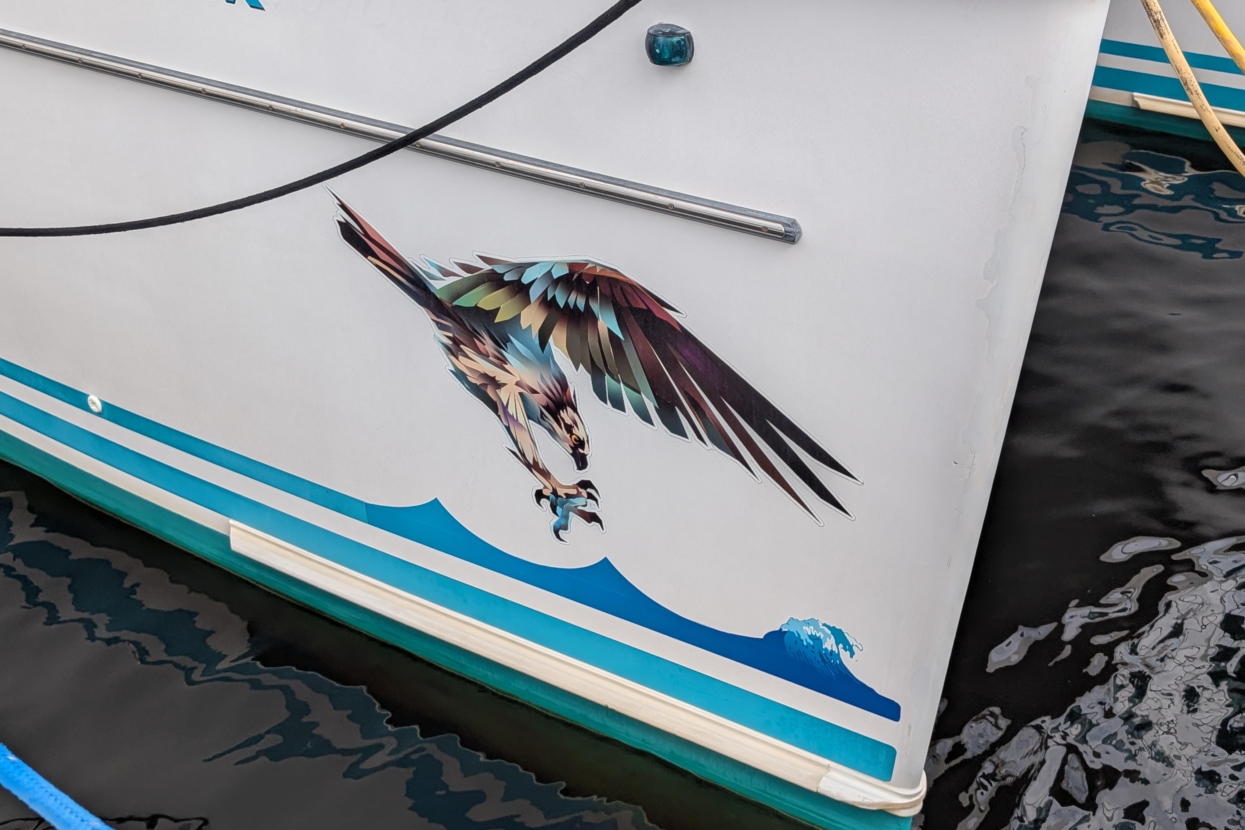 2004 PDQ 34 Powercat with eagle graphic on hull, docked on water.