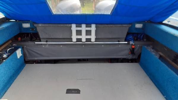 Interior of a boat with a blue cover and gray flooring.