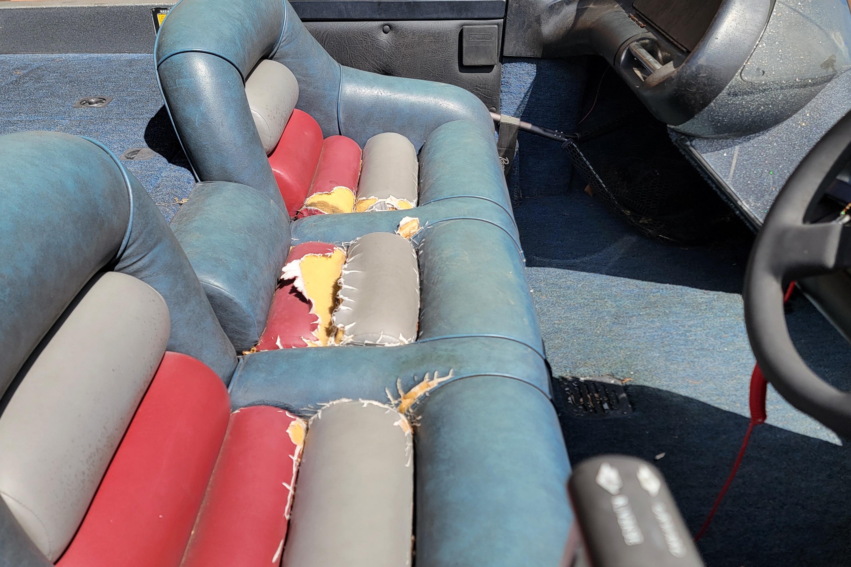 1995 Ranger boat interior with worn, multicolored seats and visible damage.