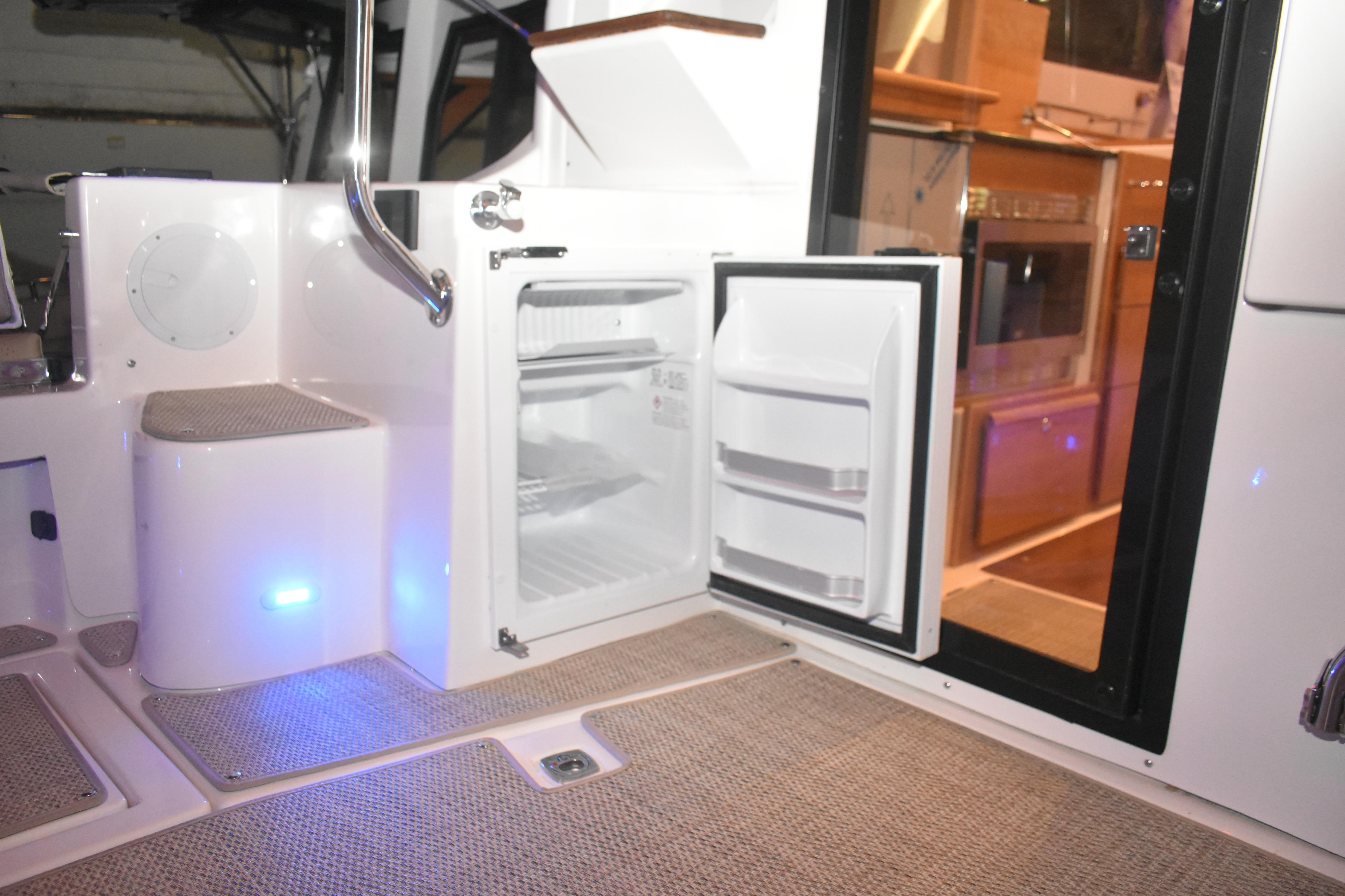 2026 Cutwater C-32 CB boat interior with open mini fridge and carpeted flooring.