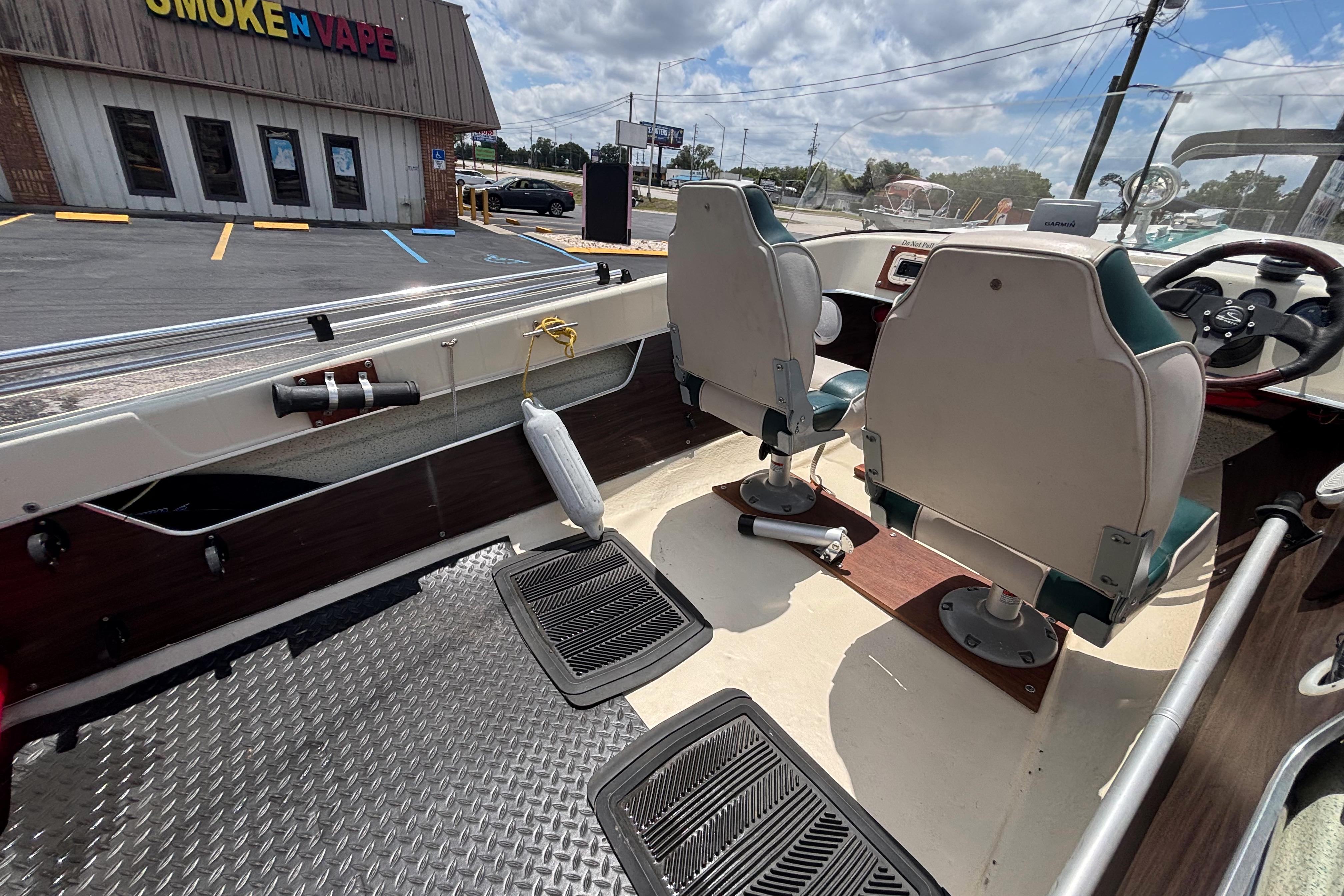 Interior of a 1966 Mohawk 15 boat with two seats, parked near a store.