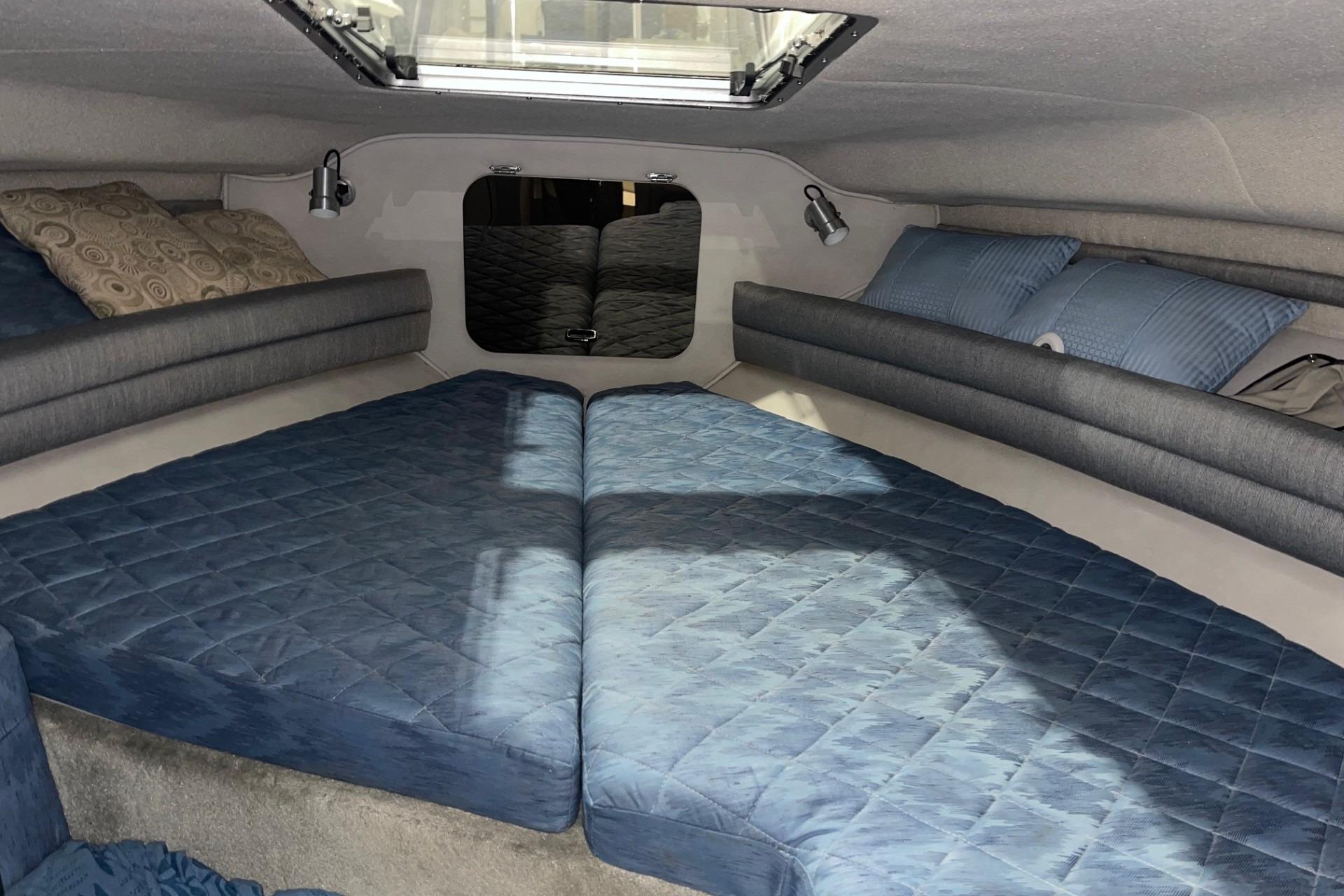 Interior cabin of 1992 Chaparral Signature 30 boat with blue bedding and pillows.