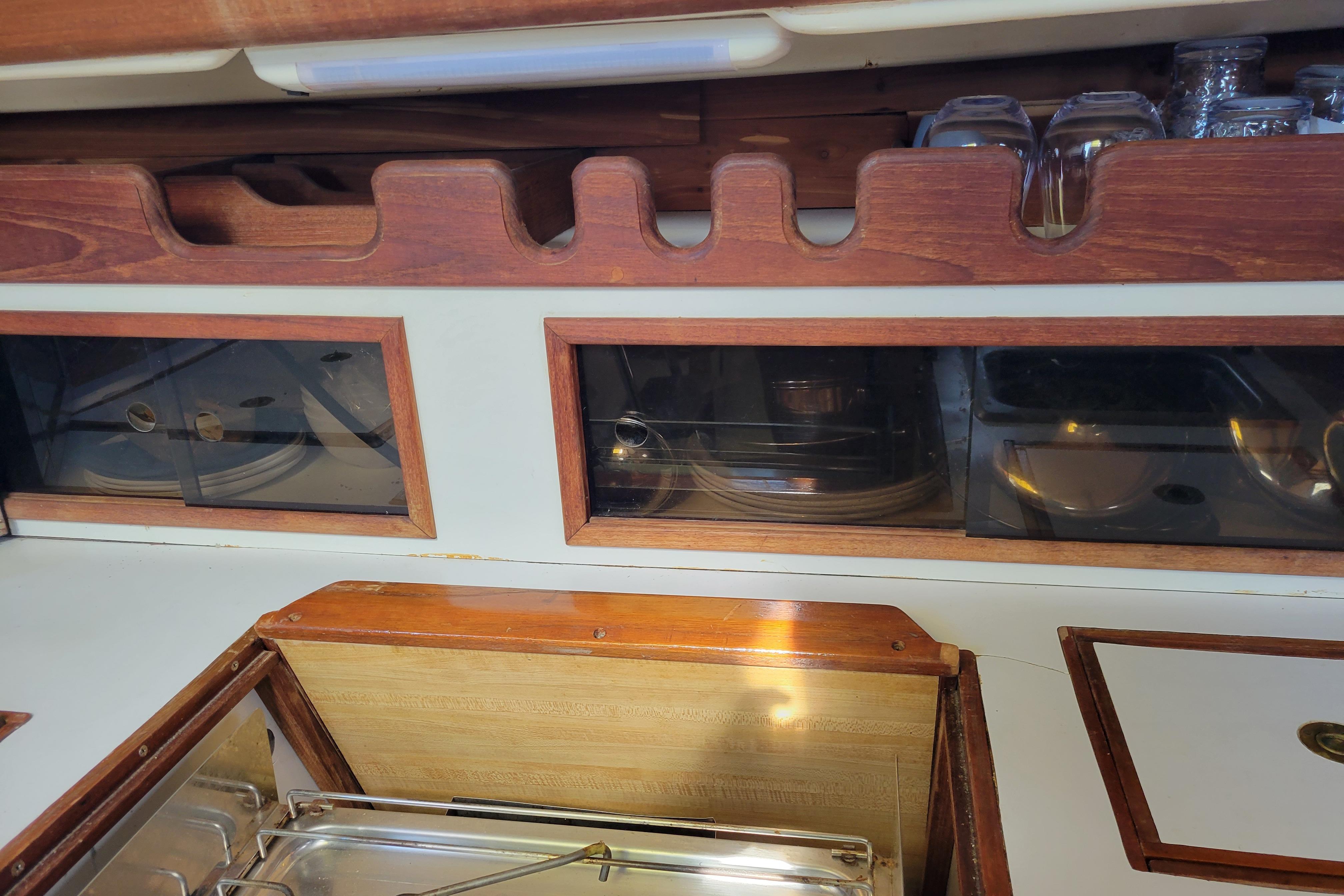 Interior of 1981 Sea Sprite 34 sailboat galley with wooden cabinetry and glass storage.