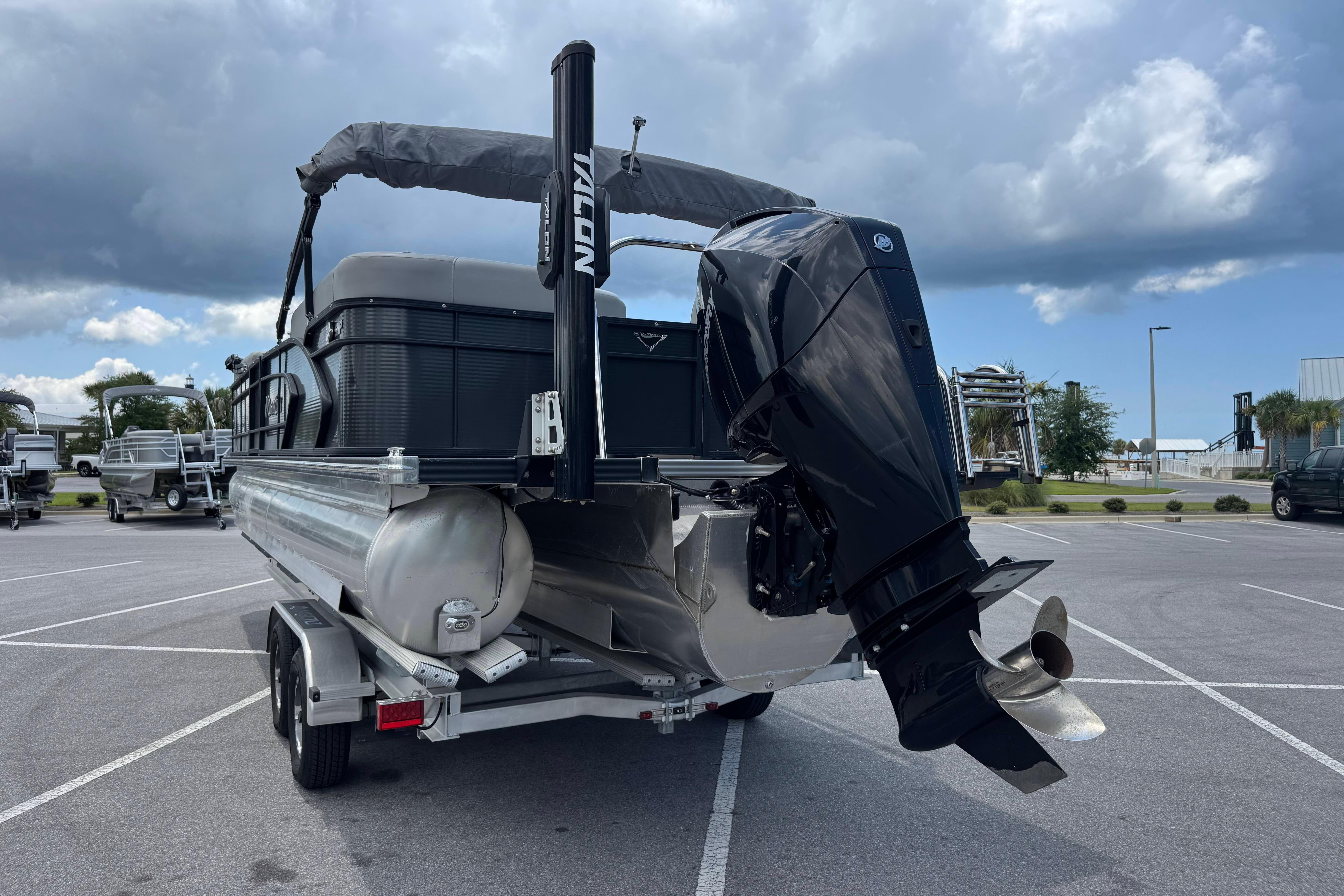 2022 Manitou 25 Encore pontoon boat with powerful outboard motor in a parking lot.